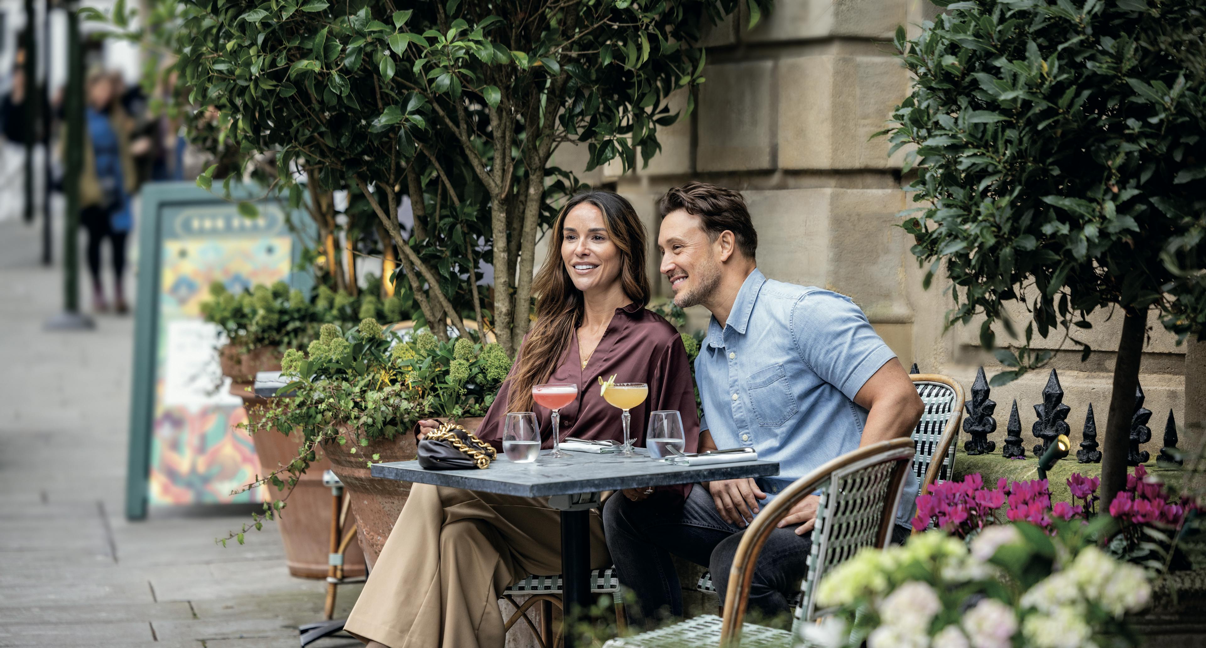 Caption: a man and a woman sitting at a table outside