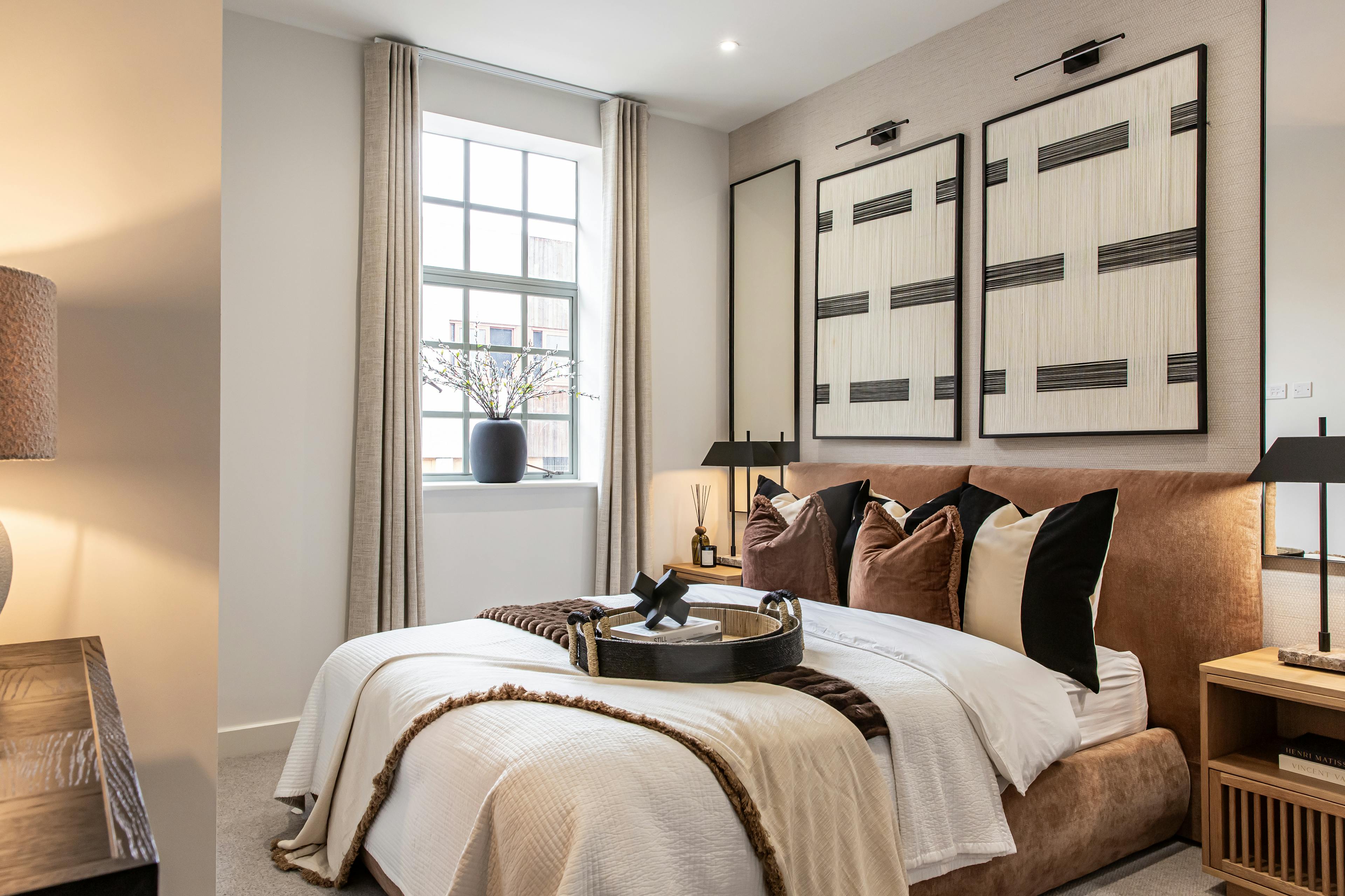 Caption: a bedroom with a bed, nightstands, lamps and pictures on the wall