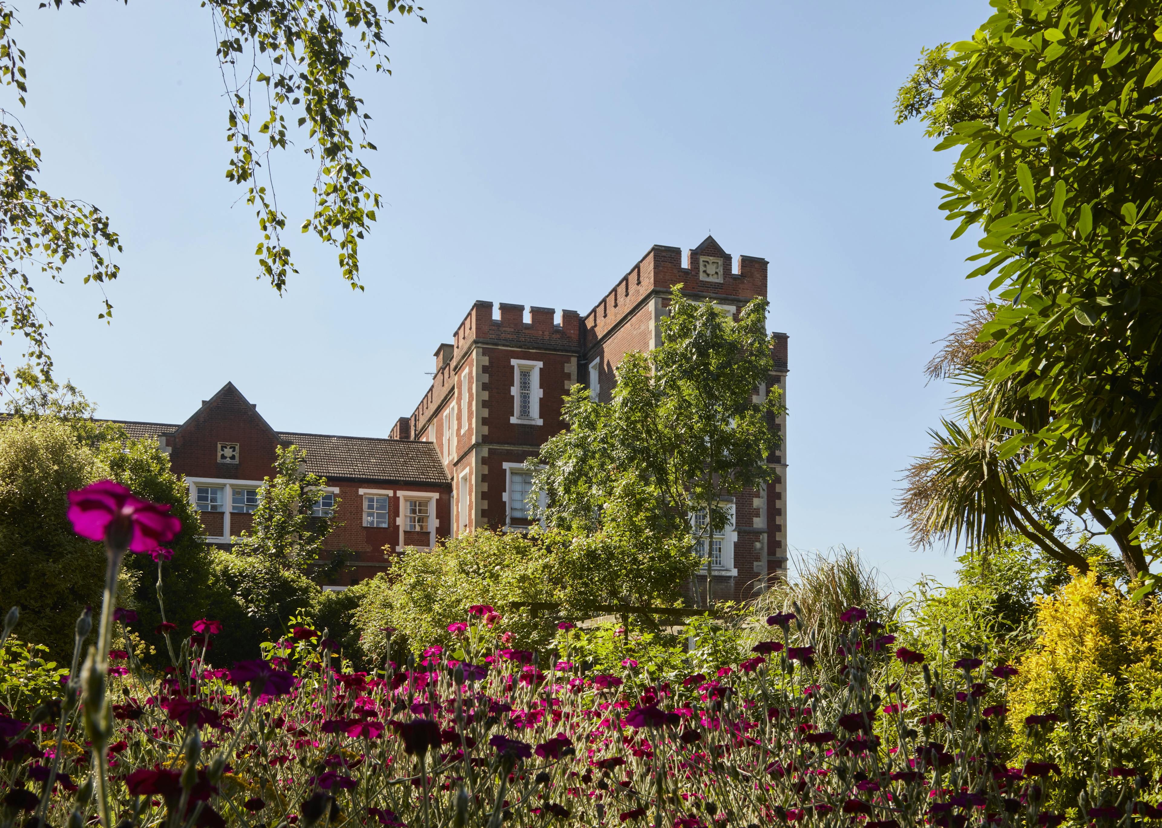 Caption: a large building surrounded by trees and flowers