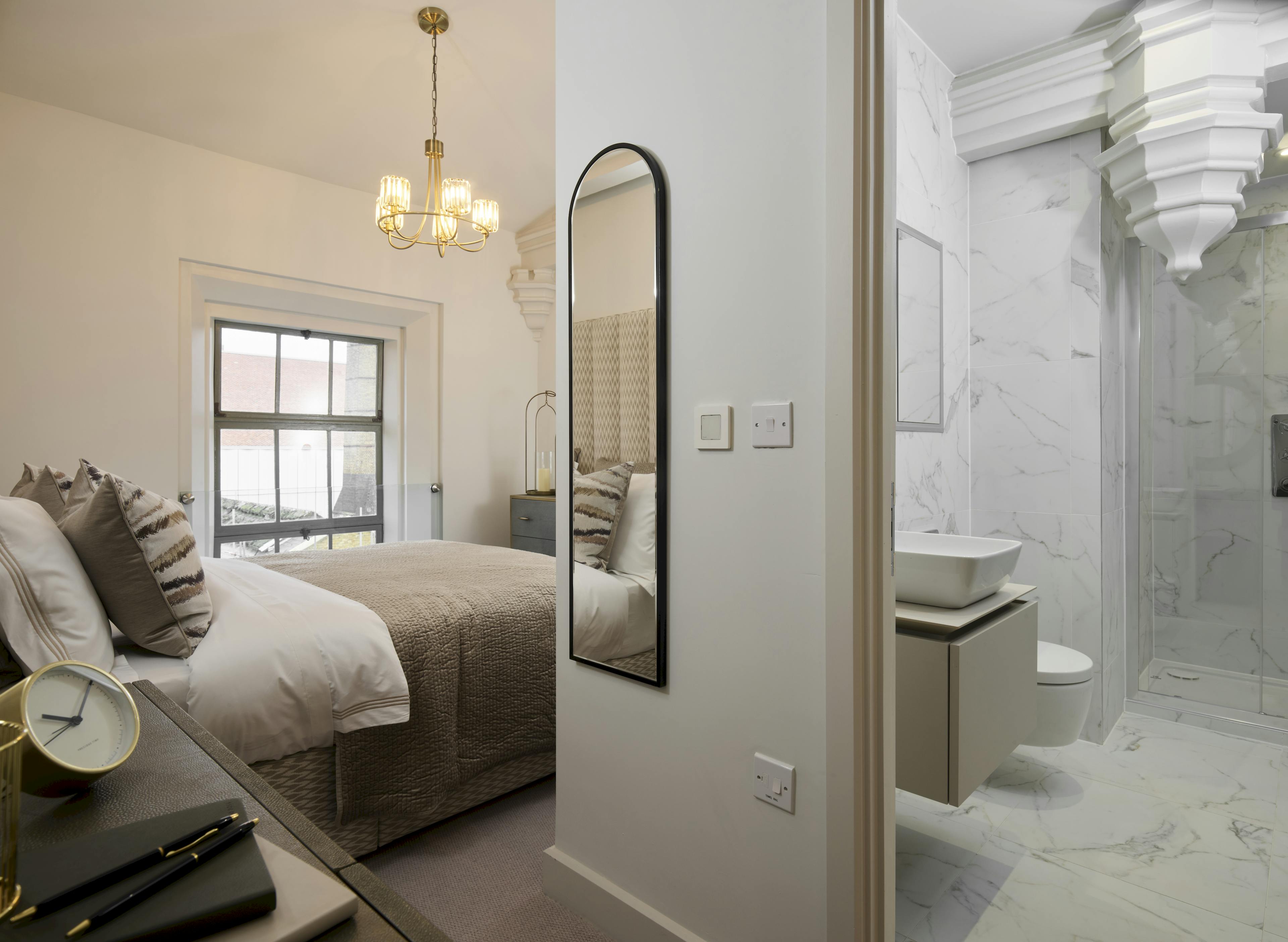 Caption: a bedroom with a large mirror and a sink