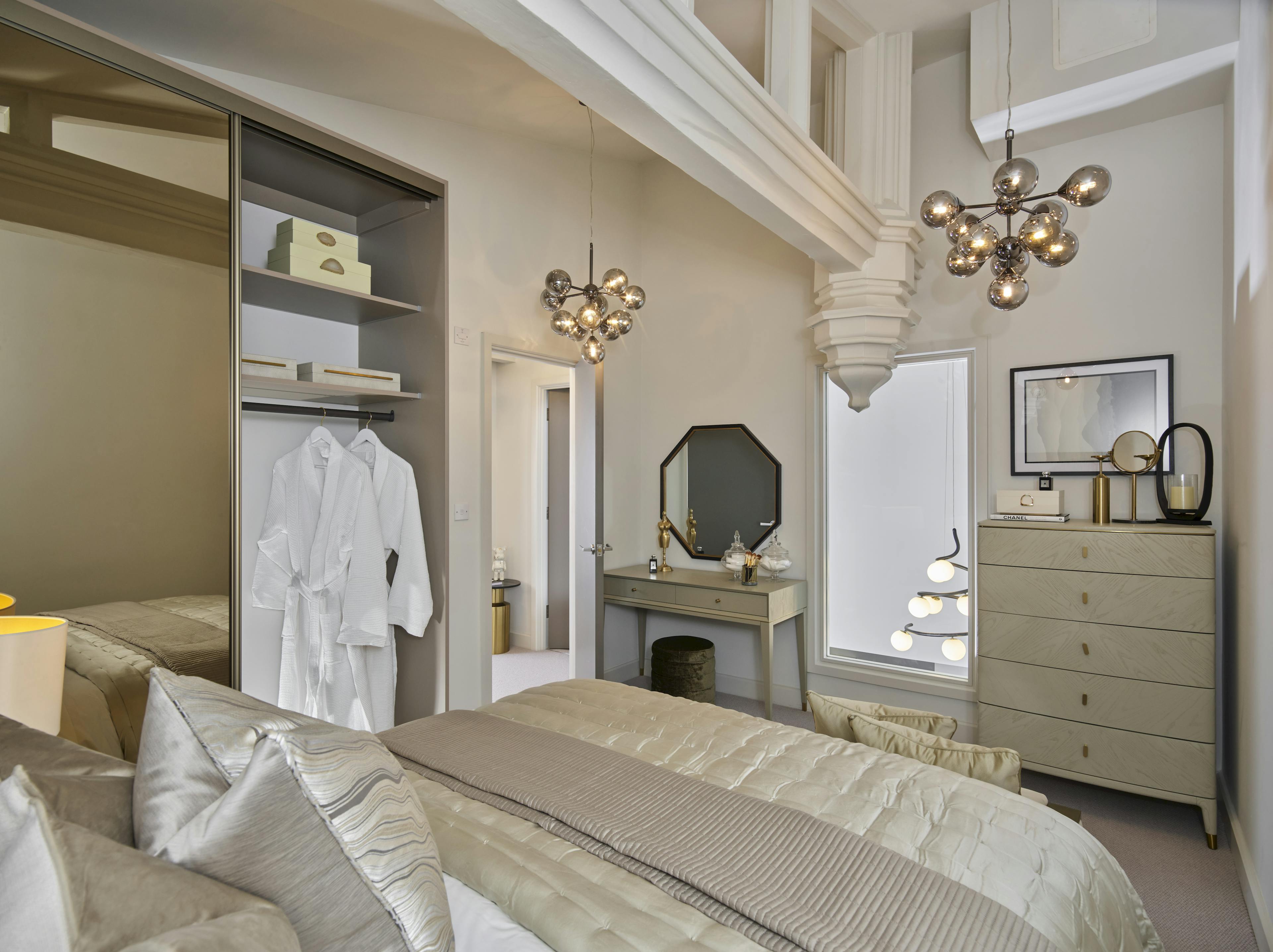 Caption: a bedroom with a bed, dresser, mirror and closet