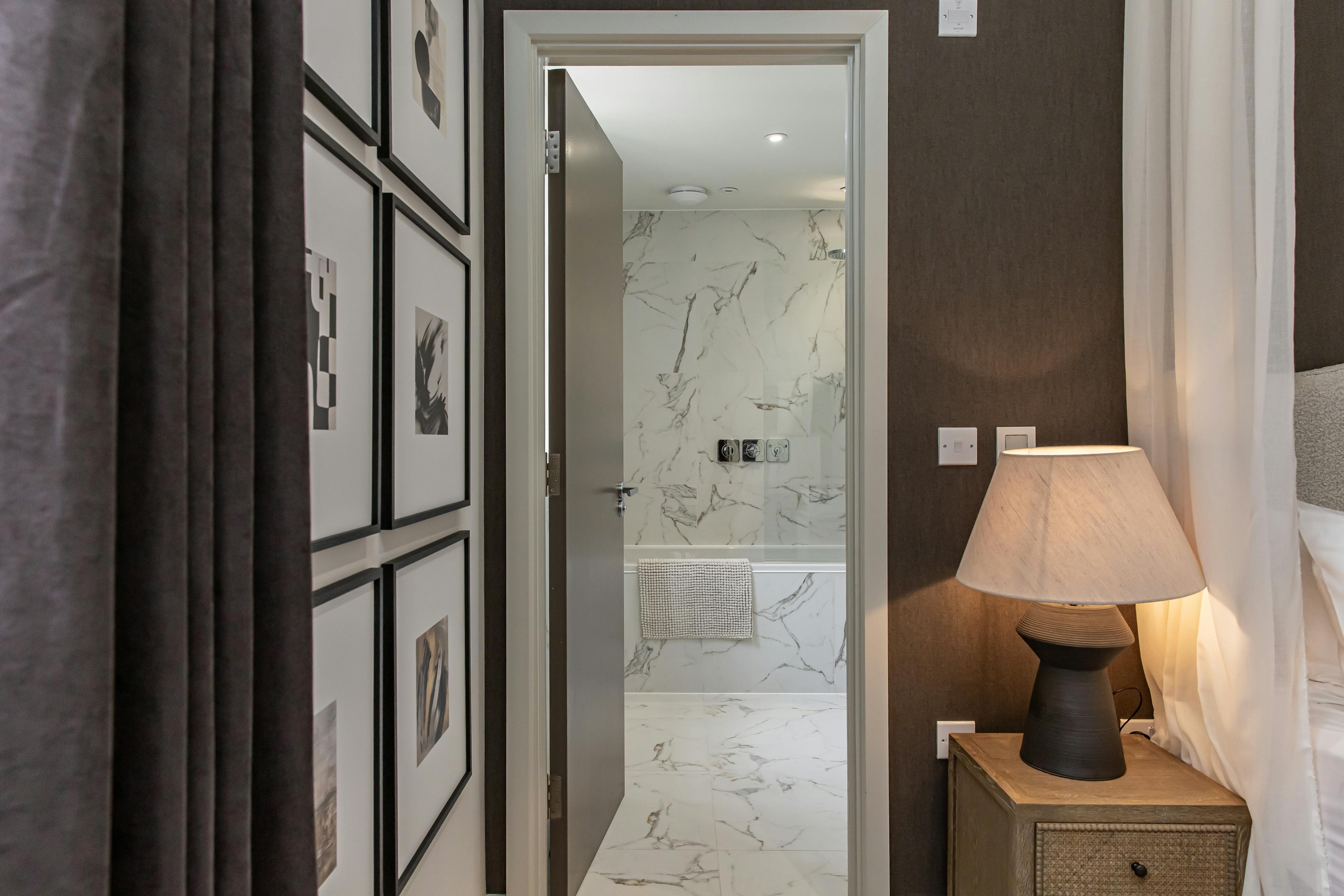 Caption: a hallway leading to a bedroom with a bed and pictures on the wall