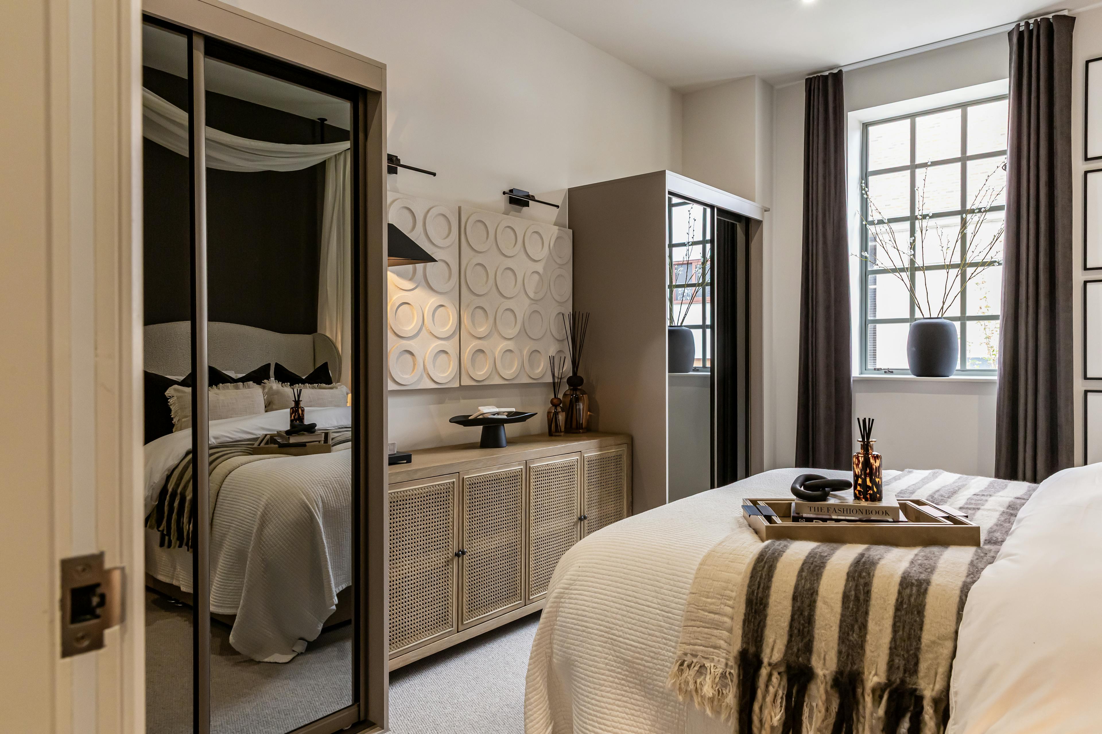 Caption: a bedroom with a bed, dresser and mirror