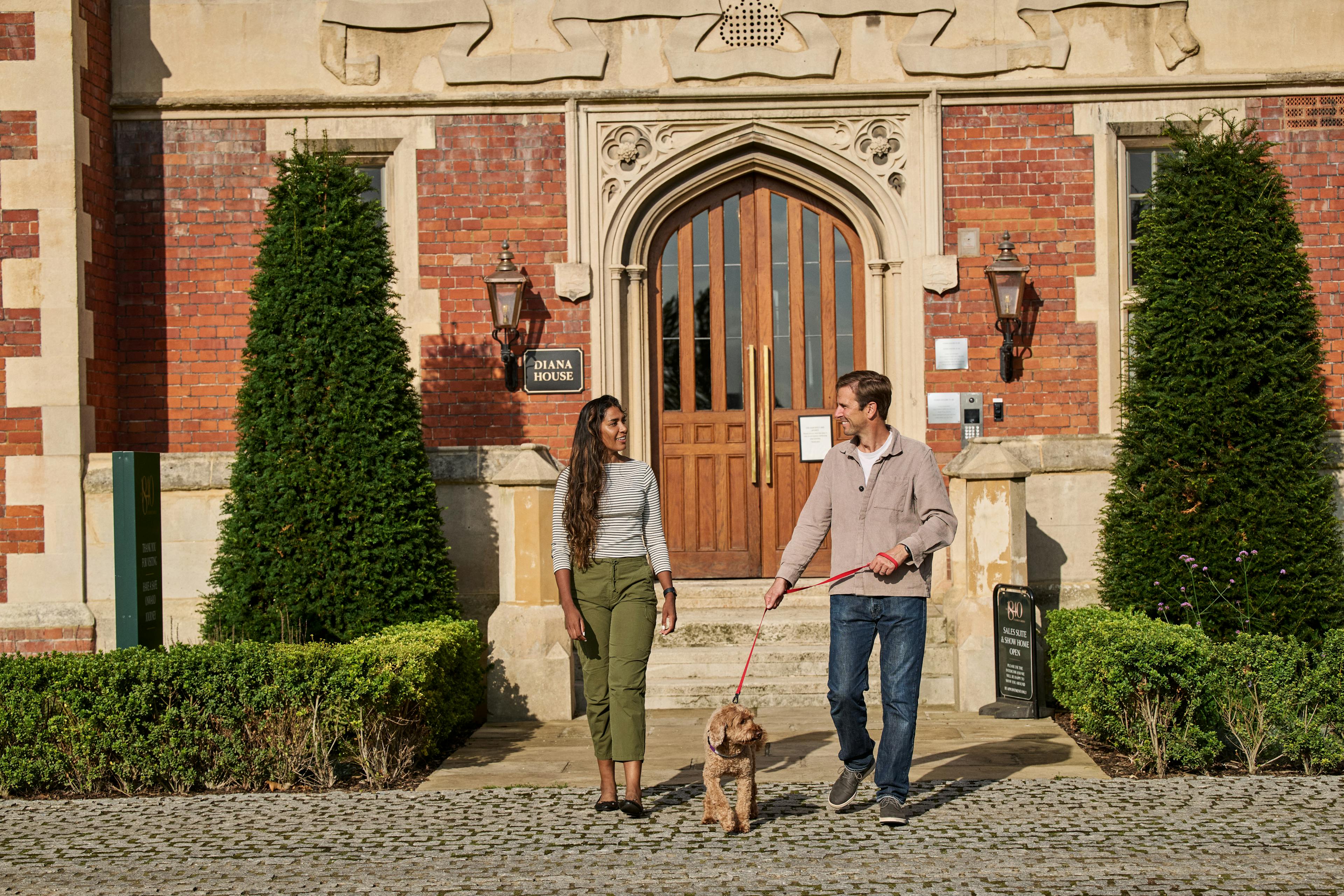 Caption: a man and woman walking a dog in front of a building