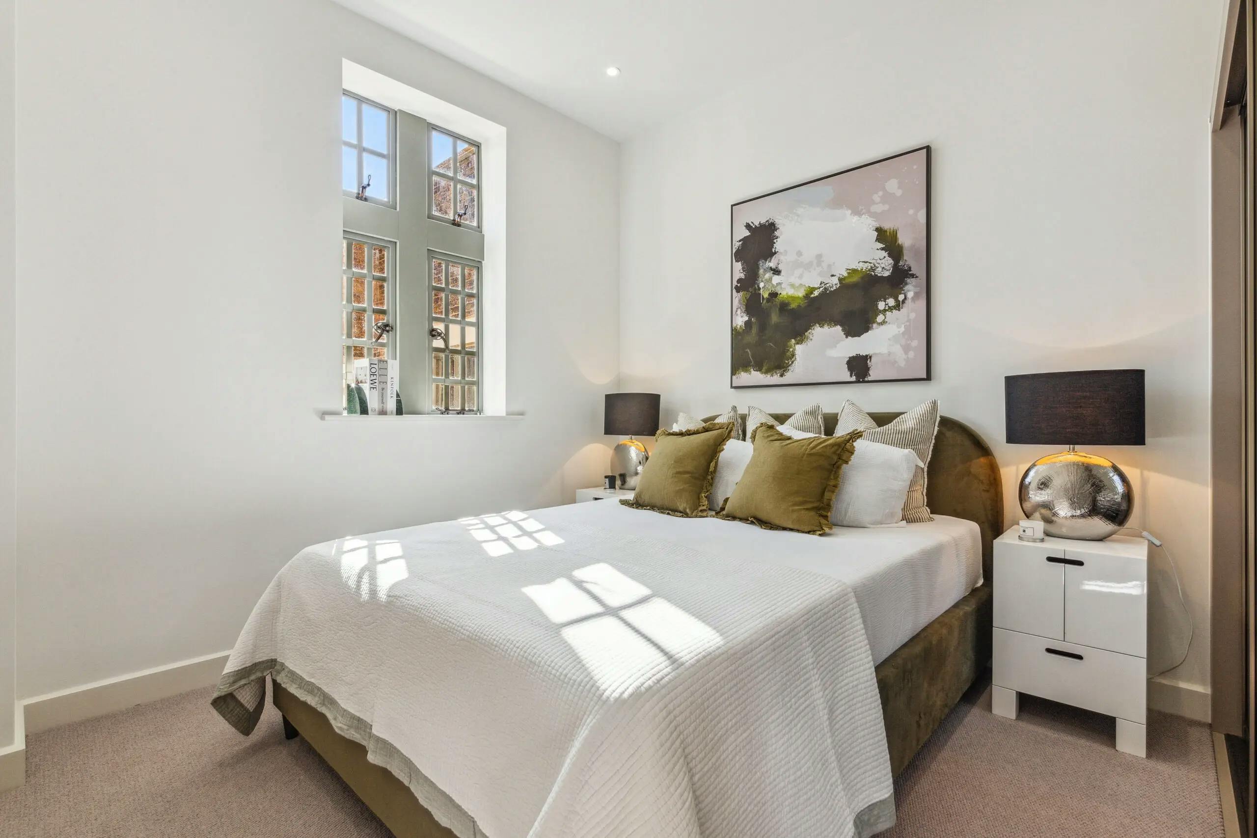 Caption: a bedroom with a large bed and a painting on the wall