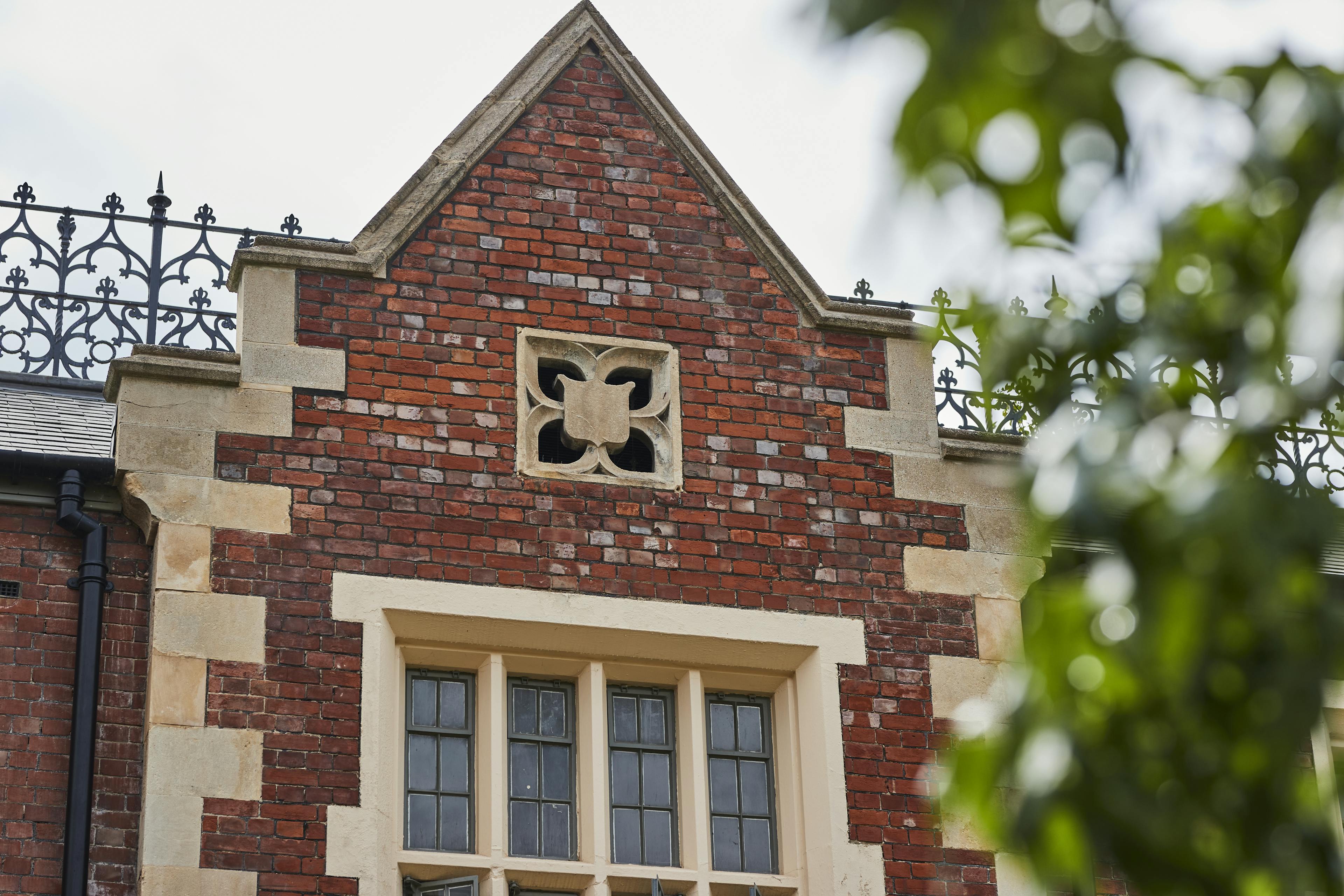 Caption: a brick building with a window and a wrought iron fence