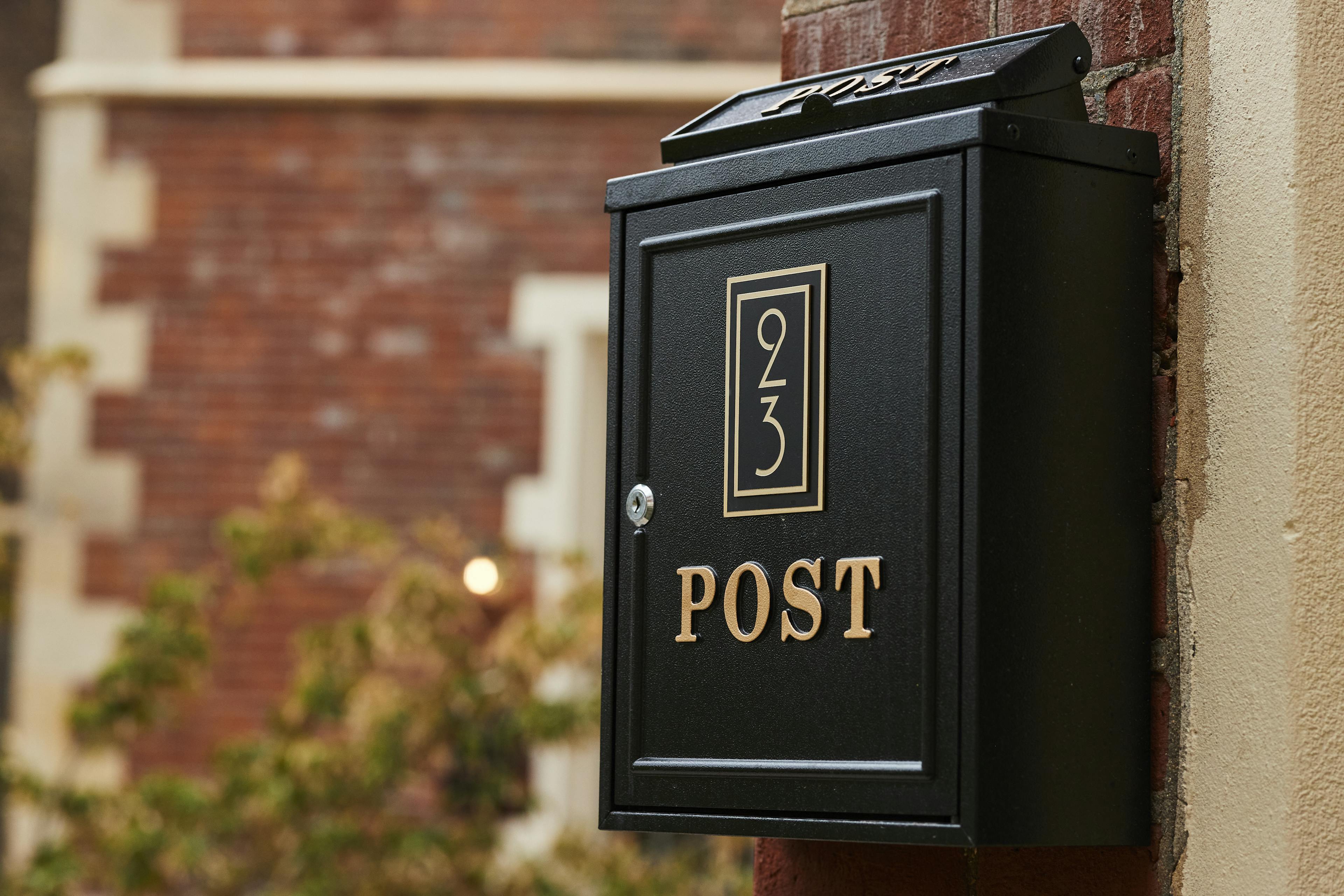 Caption: a black mailbox attached to a brick wall