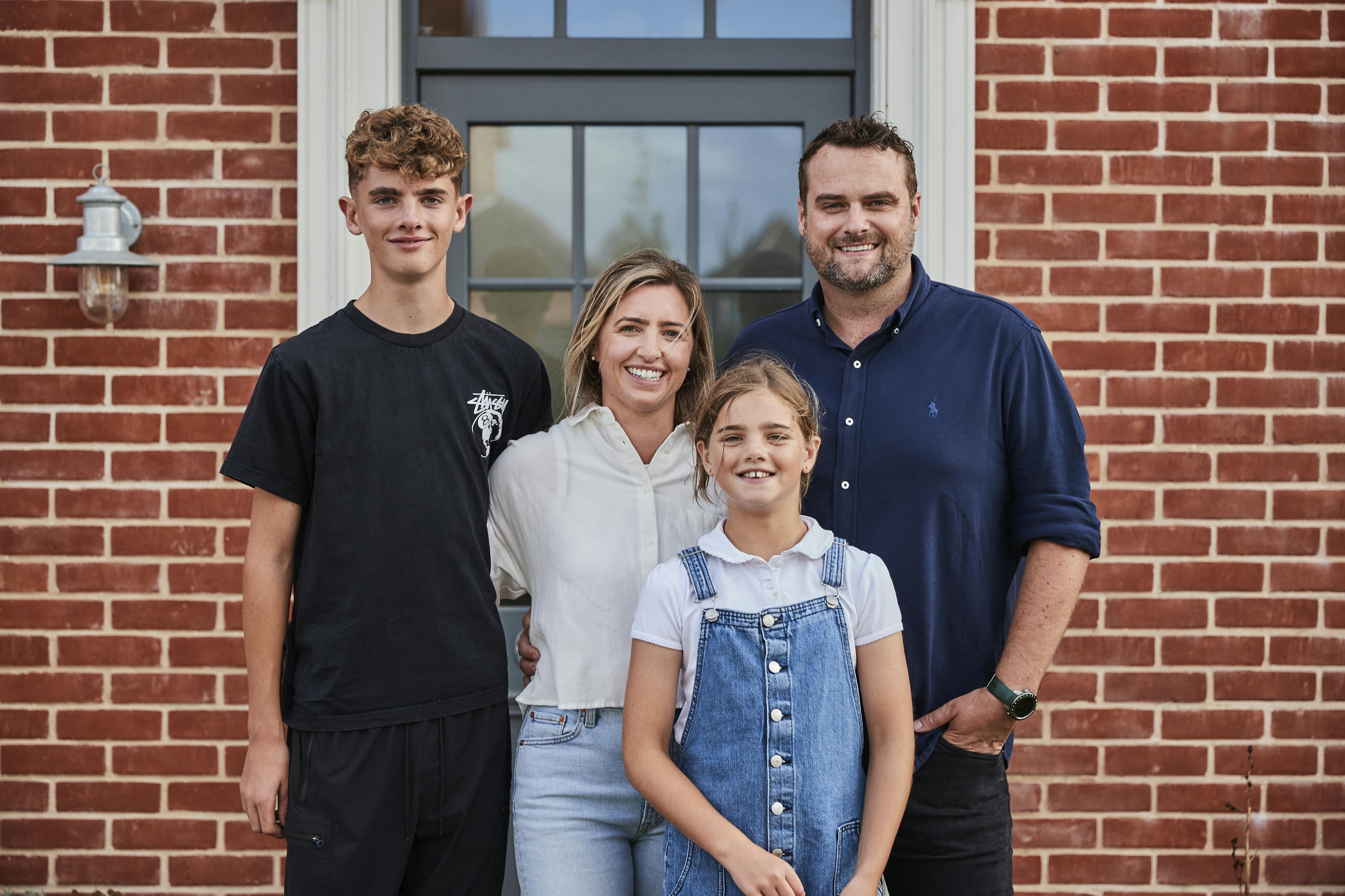 Caption: a family poses for a picture in front of a brick building