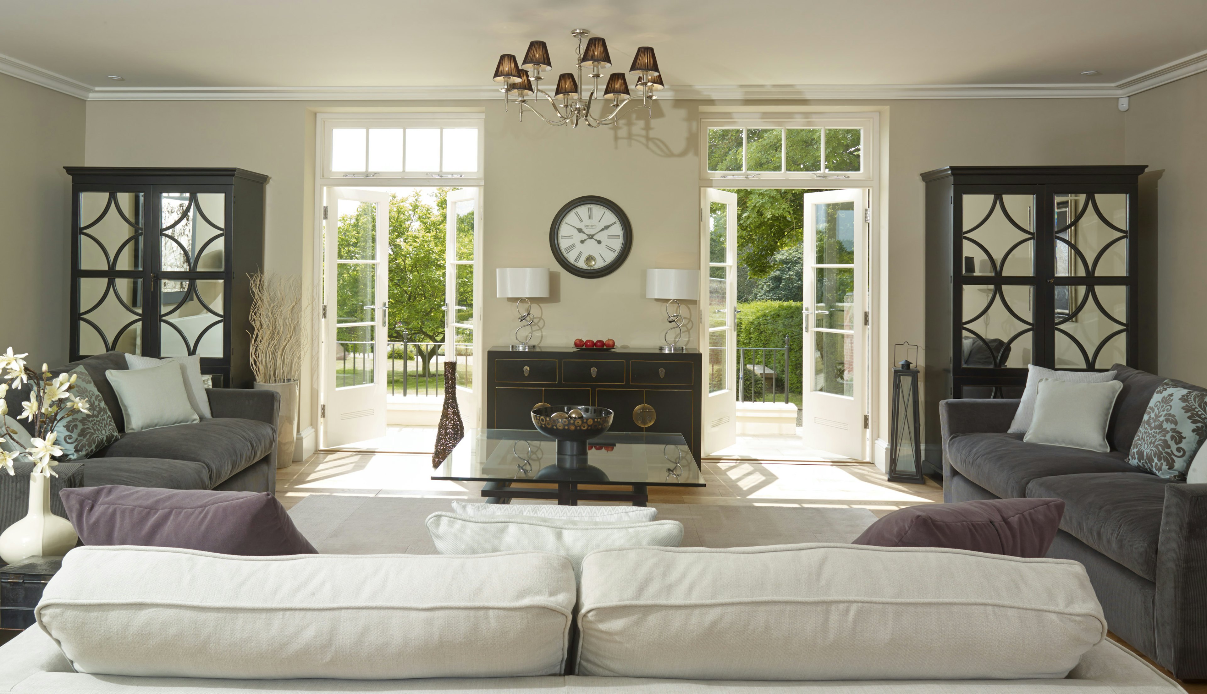 Caption: a living room filled with furniture and a clock on the wall
