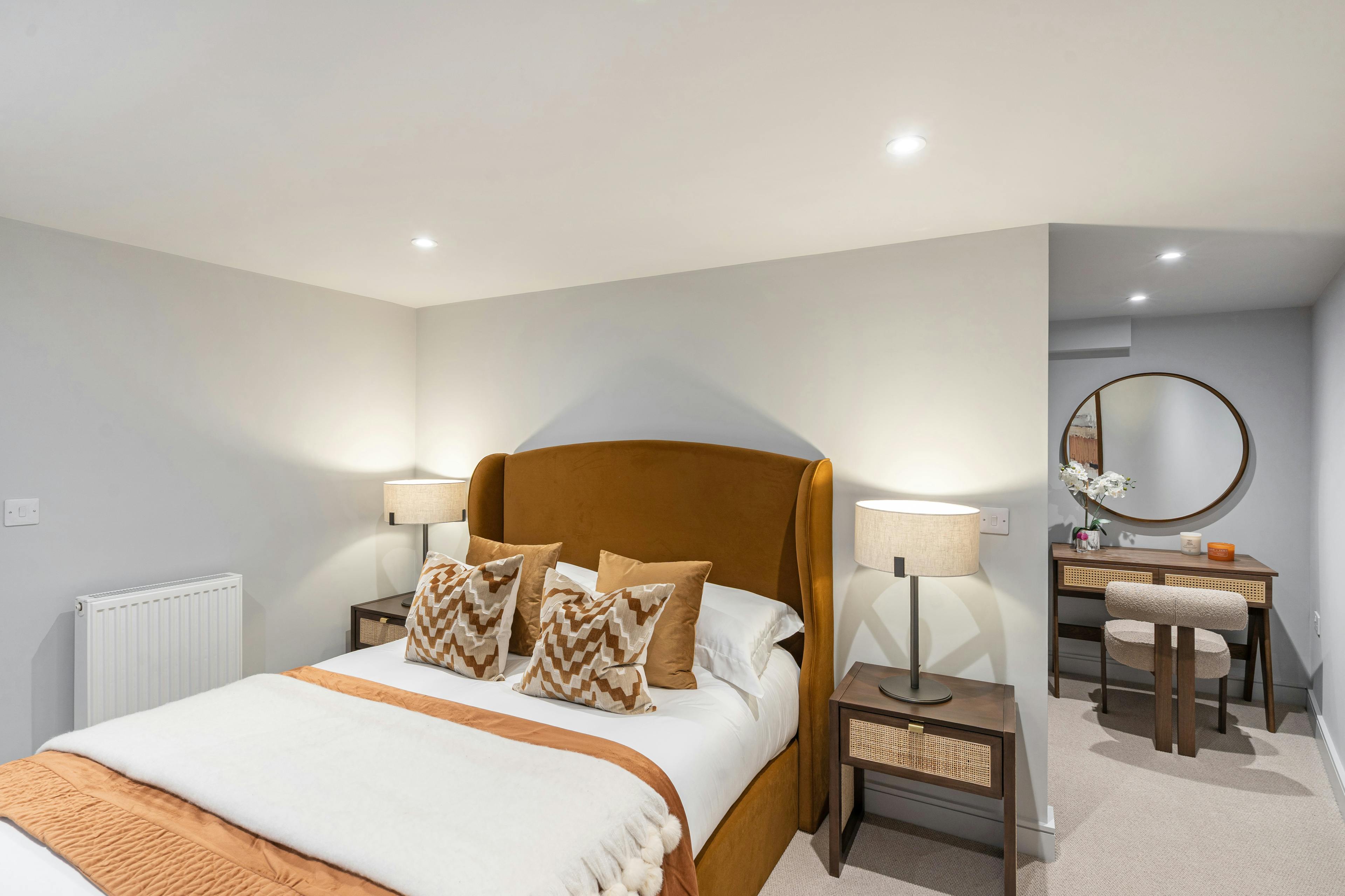 Caption: a bedroom with a bed, dresser, and mirror