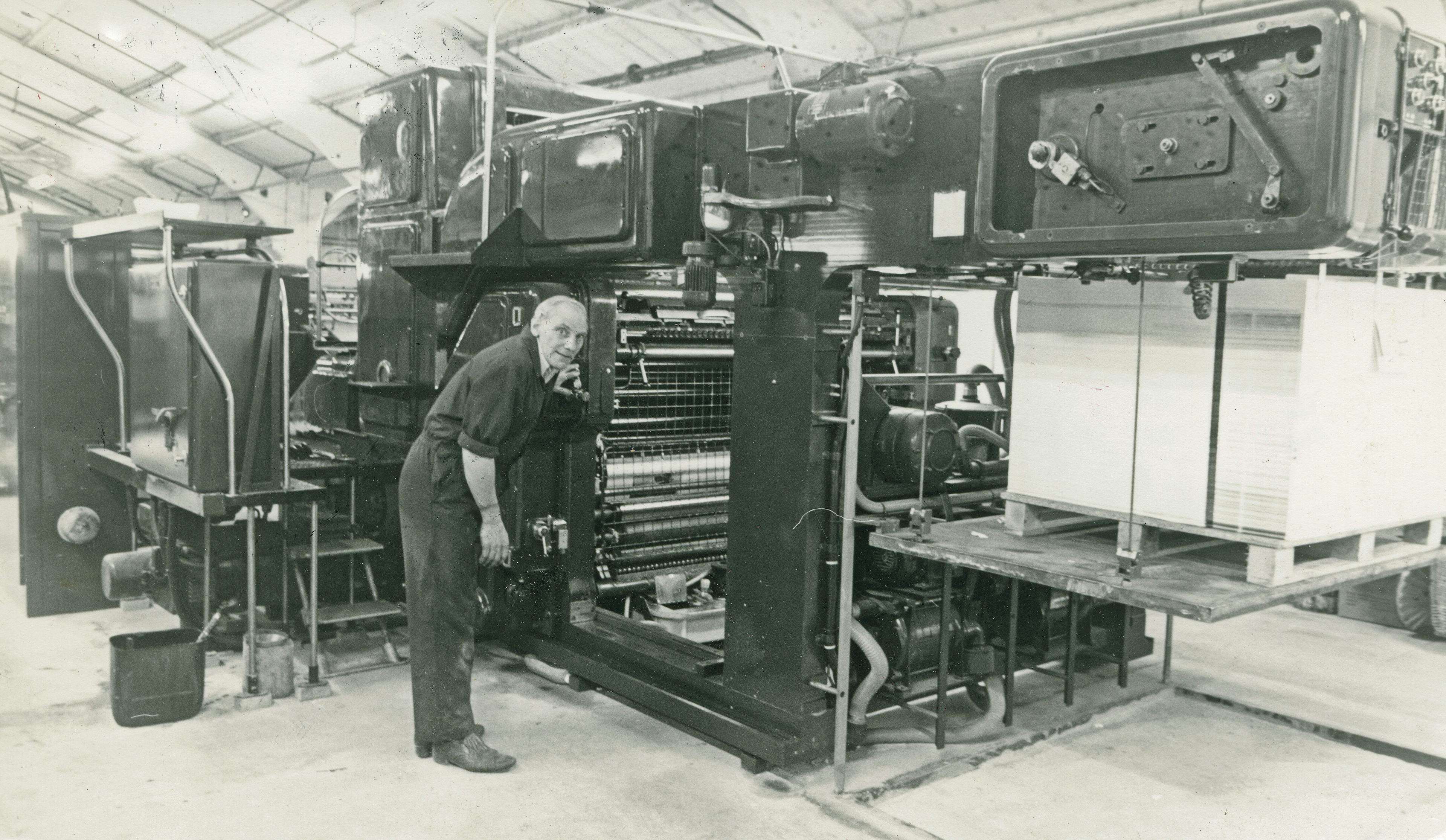 Caption: a man standing in front of a machine in a factory