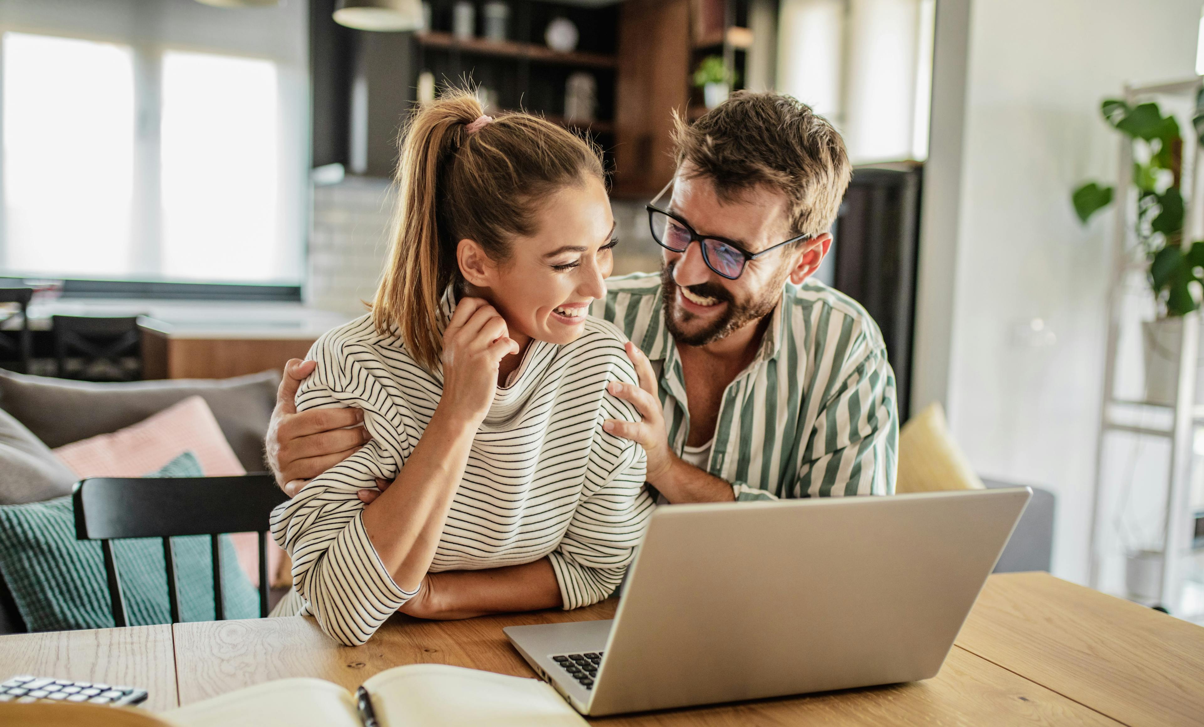 Caption: a man and woman sitting at a table looking at a laptop