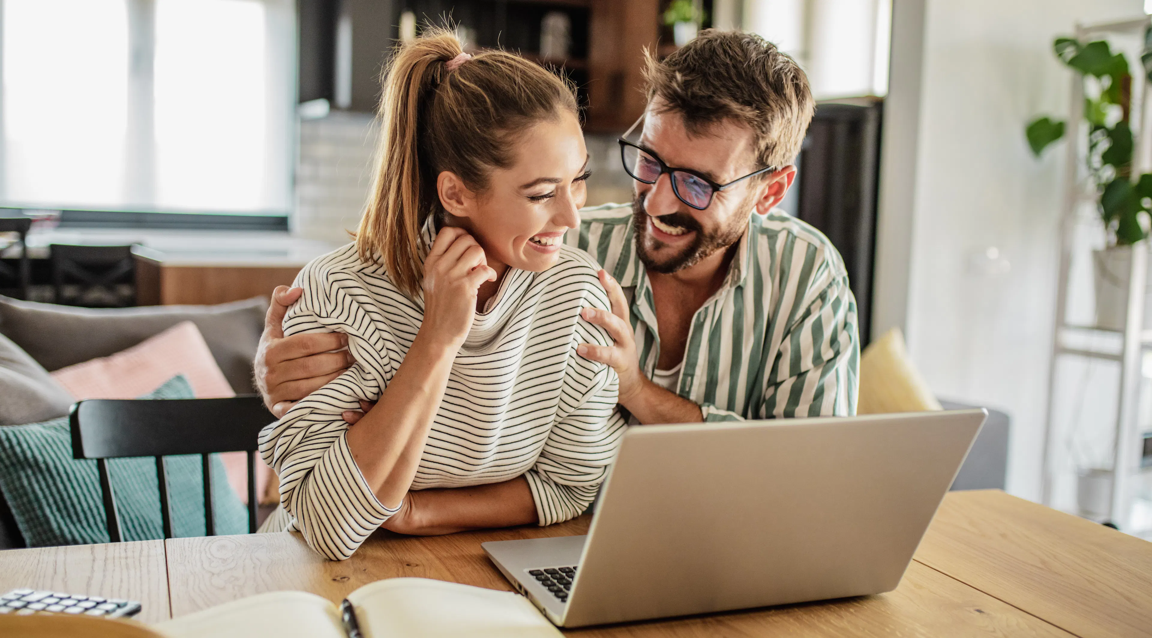 Caption: a man and woman sitting at a table looking at a laptop
