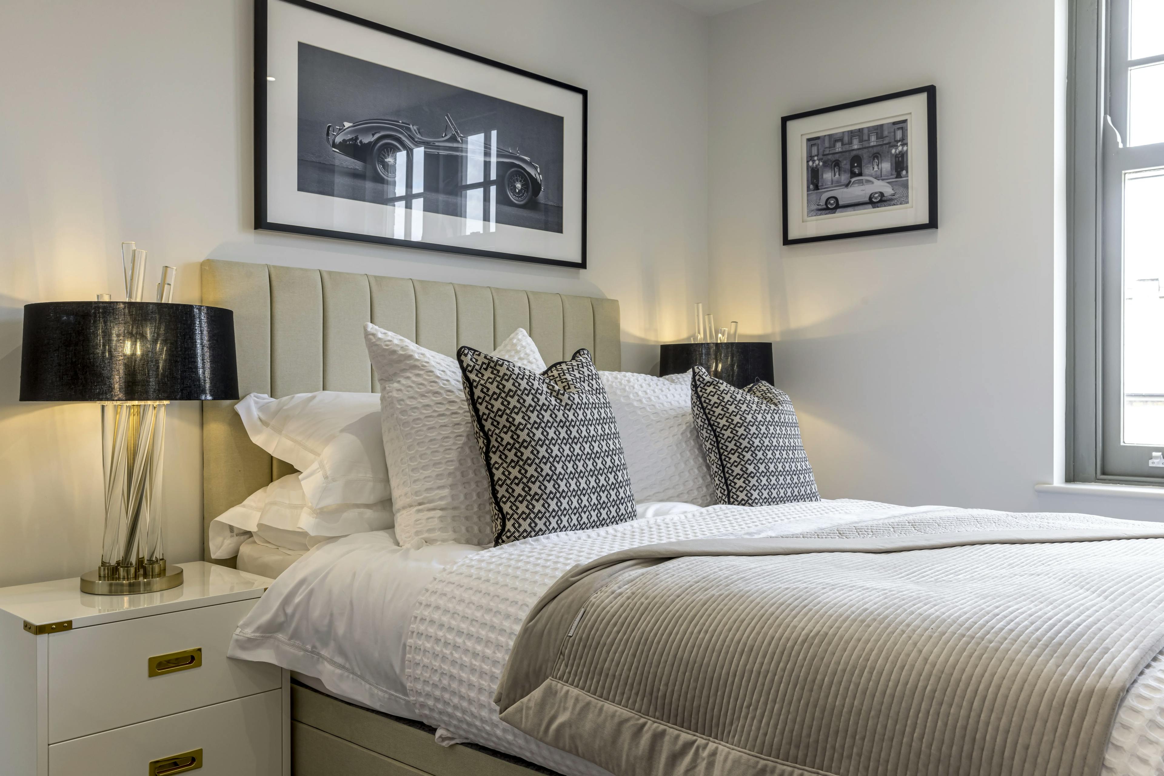 Caption: a bedroom with a white bed and two framed pictures on the wall