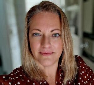 Caption: a woman in a polka dot shirt looking at the camera