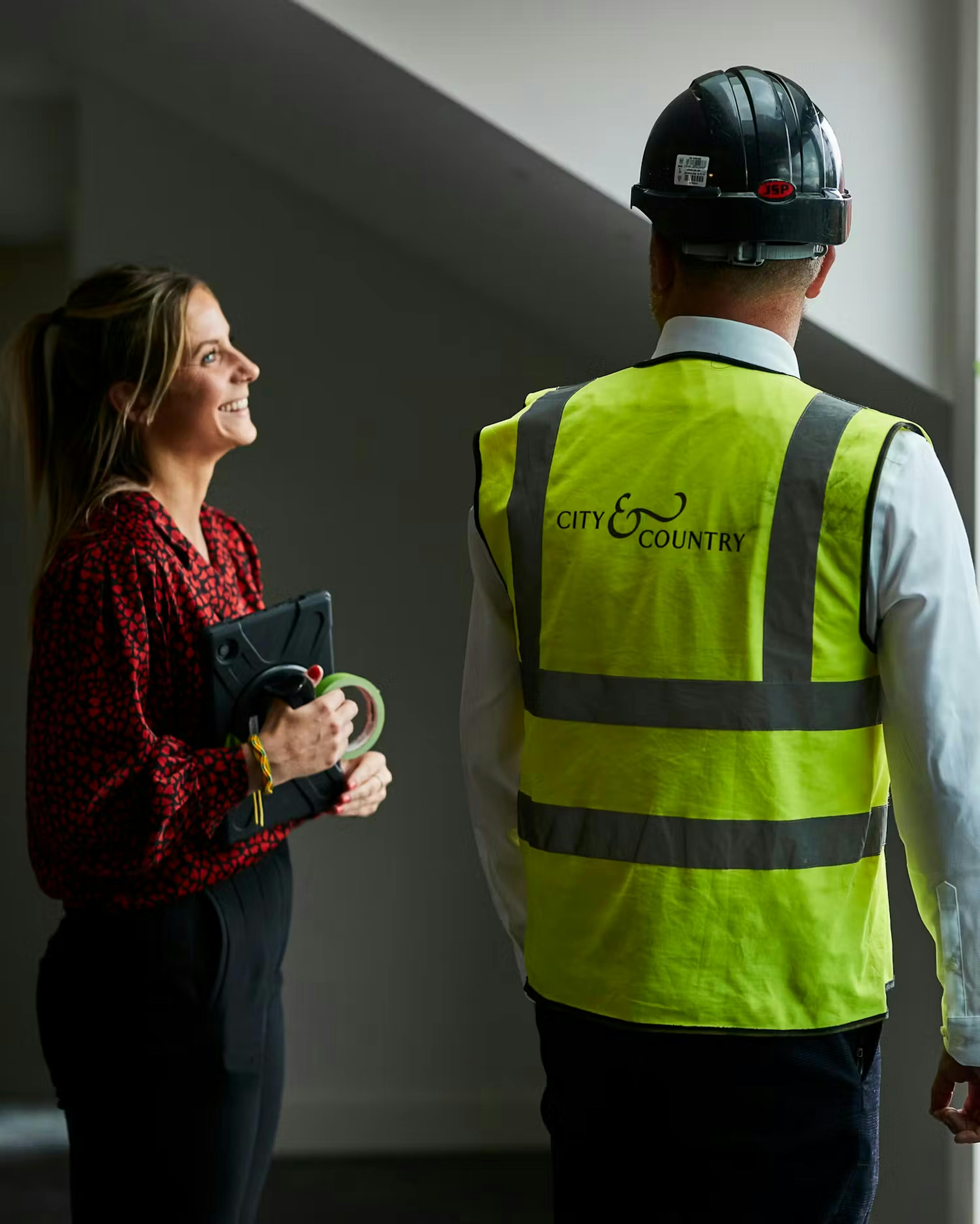 Caption: a man and a woman wearing safety vests and hard hats