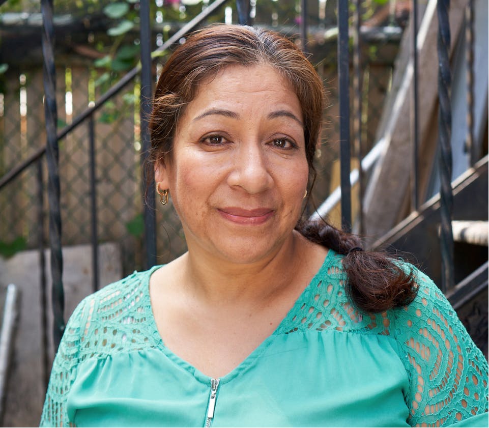 Woman wearing a turquoise blouse smiling optimistically.