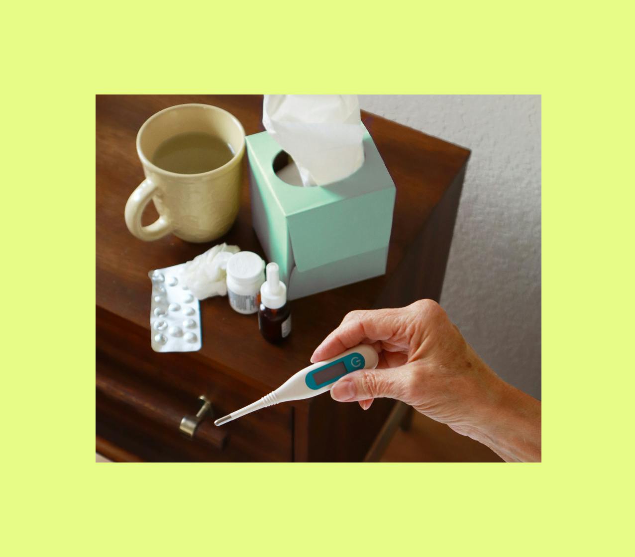 Person checks body temperature with a thermometer at the bedside for symptoms of a fever.