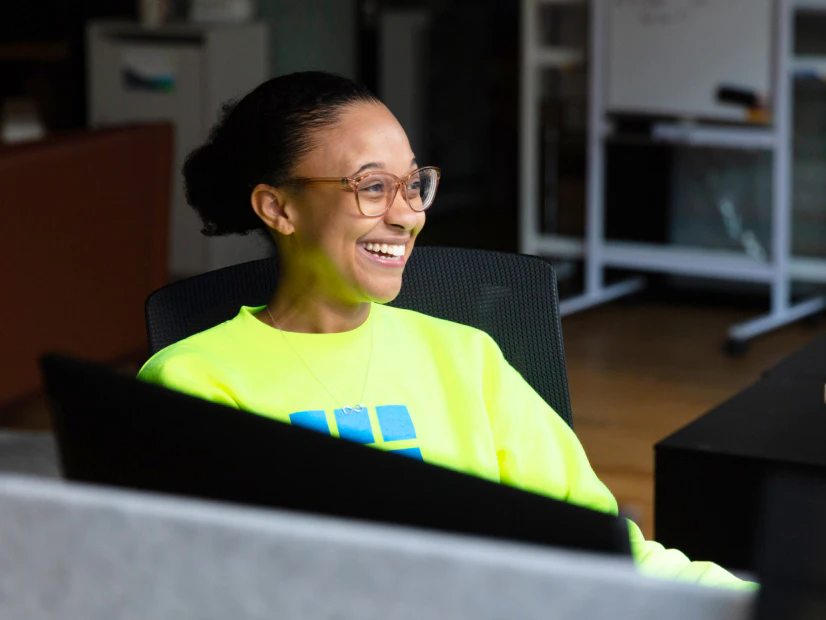 Image of a Cityblock employee with glasses and a neon yellow sweatshirt sitting at her office desk.