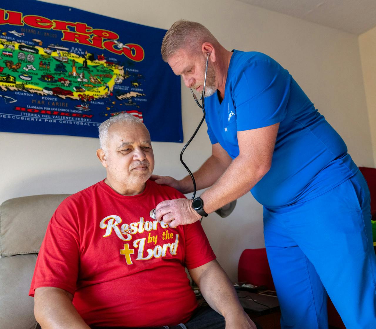 Cityblock employee wearing blue scrubs doing a check-up on member wearing a red tshirt.