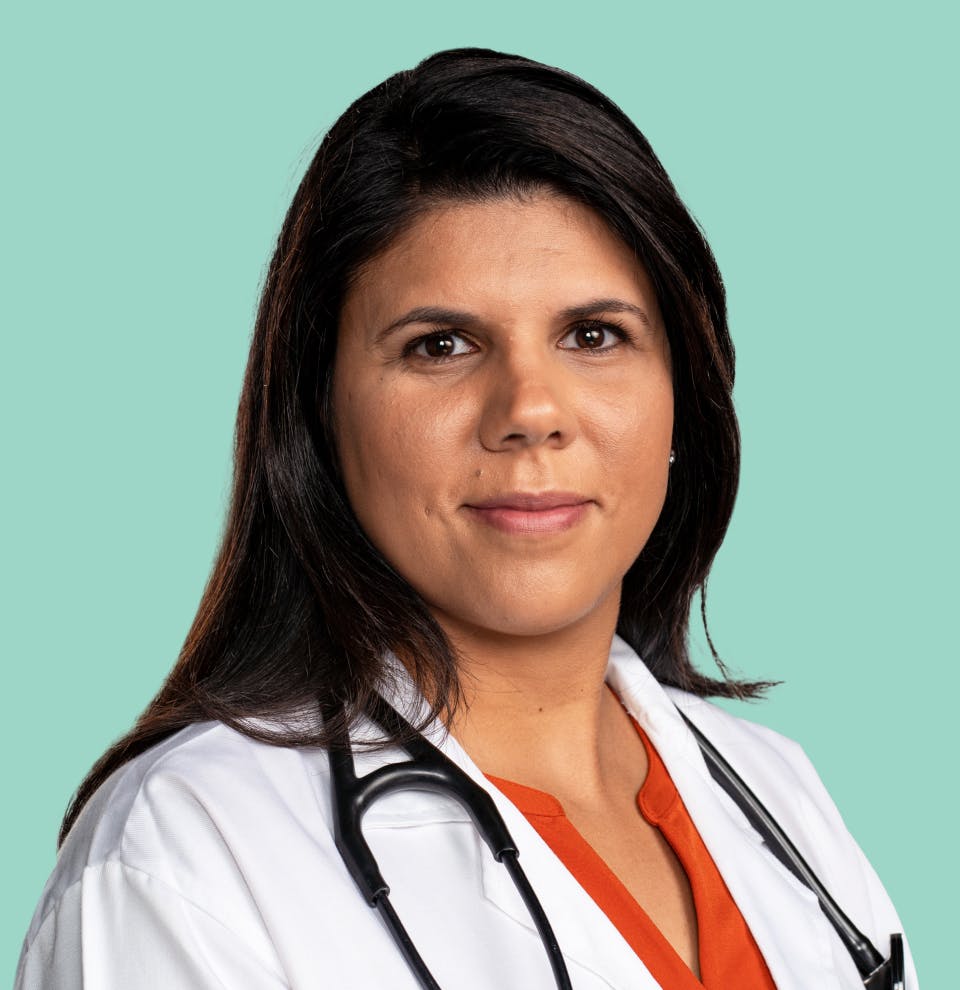 Woman smiles proudly on a teal background.