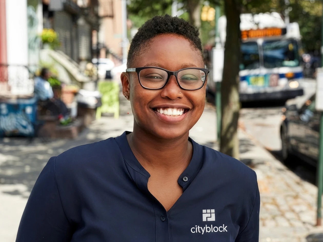 Image of a community health partner wearing a navy blue Cityblock shirt while smiling and wearing glasses.
