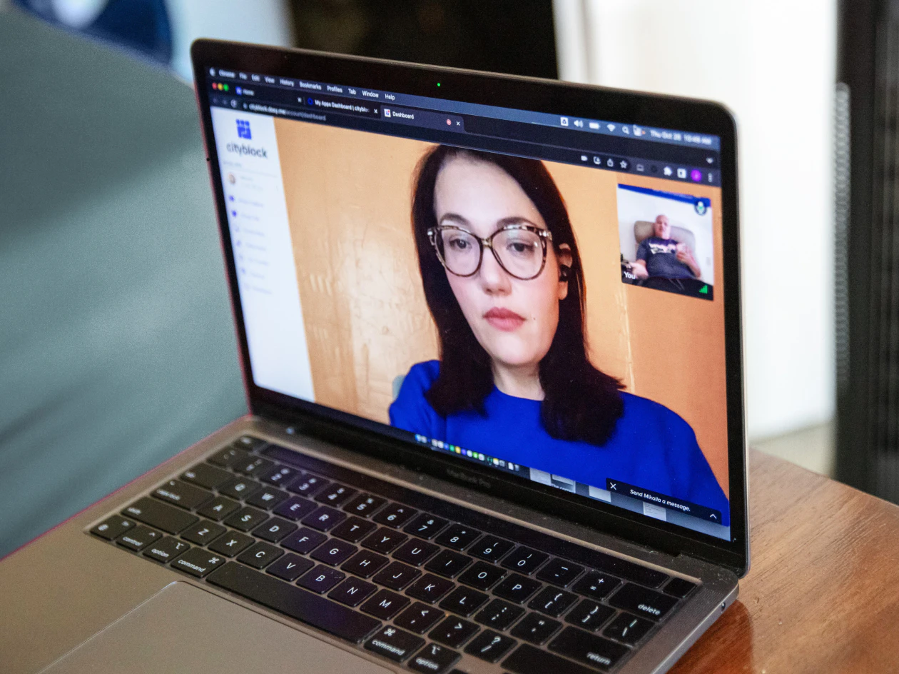 Image of an open laptop sitting on a wooden table, displaying a live healthcare worker on the video call.