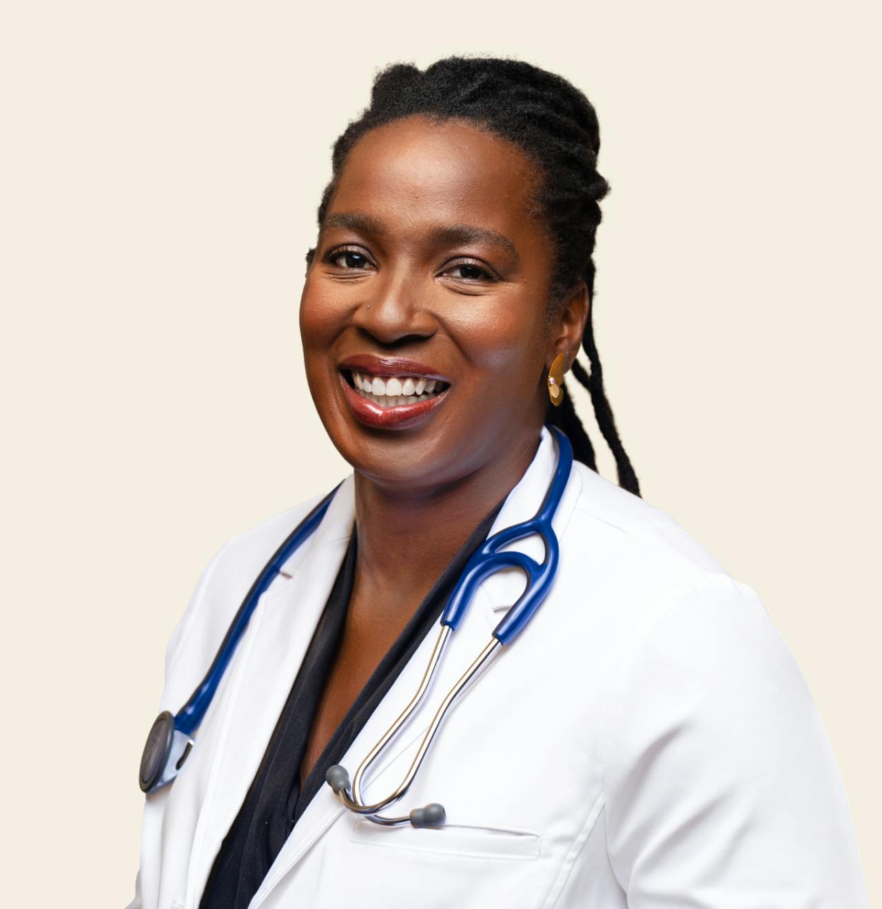 Cityblock CEO Toyin Ajayi smiles while wearing a white coat.