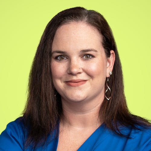 Woman smiles wearing blue scrubs.