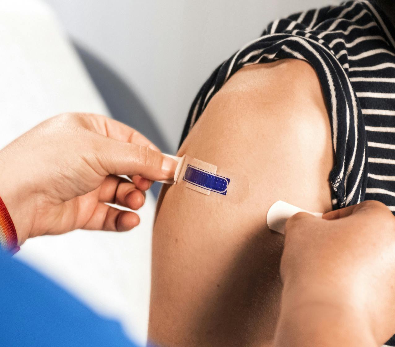 Adult gets flu vaccine and bandage by a healthcare professional to keep safe.