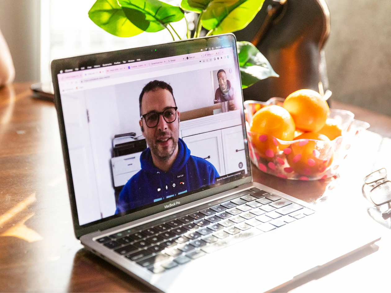 Image of a laptop screen displaying a video call with a medical provider wearing glasses.