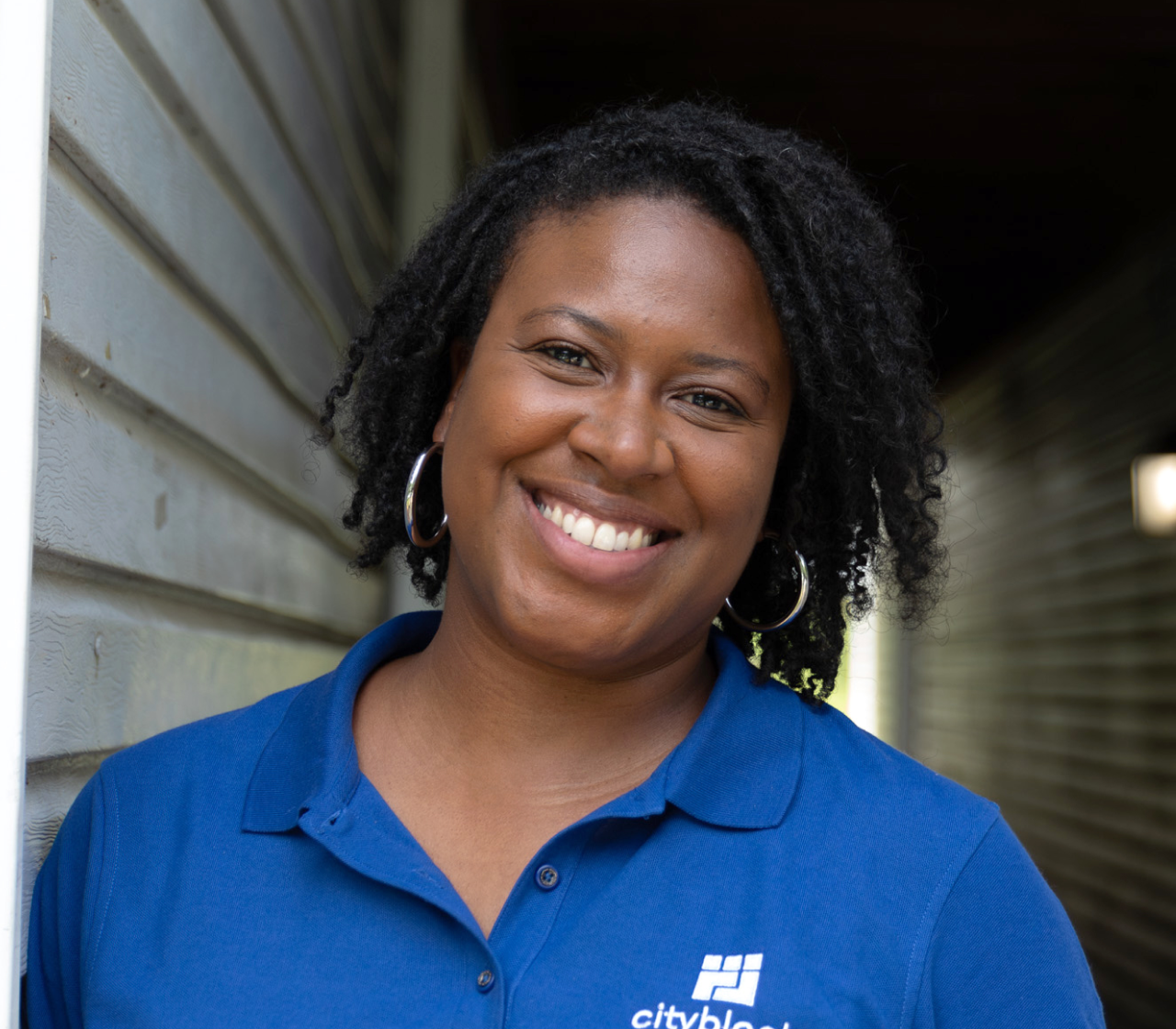 Woman smiles while wearing a blue polo shirt with Cityblock logo