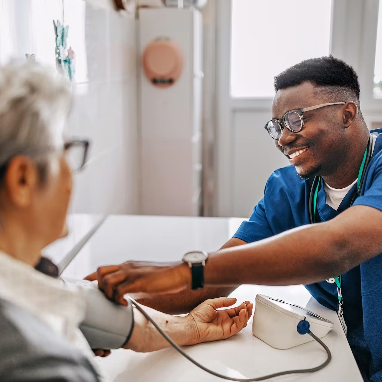 A smiling nurse taking the blood pressure reading of a patient