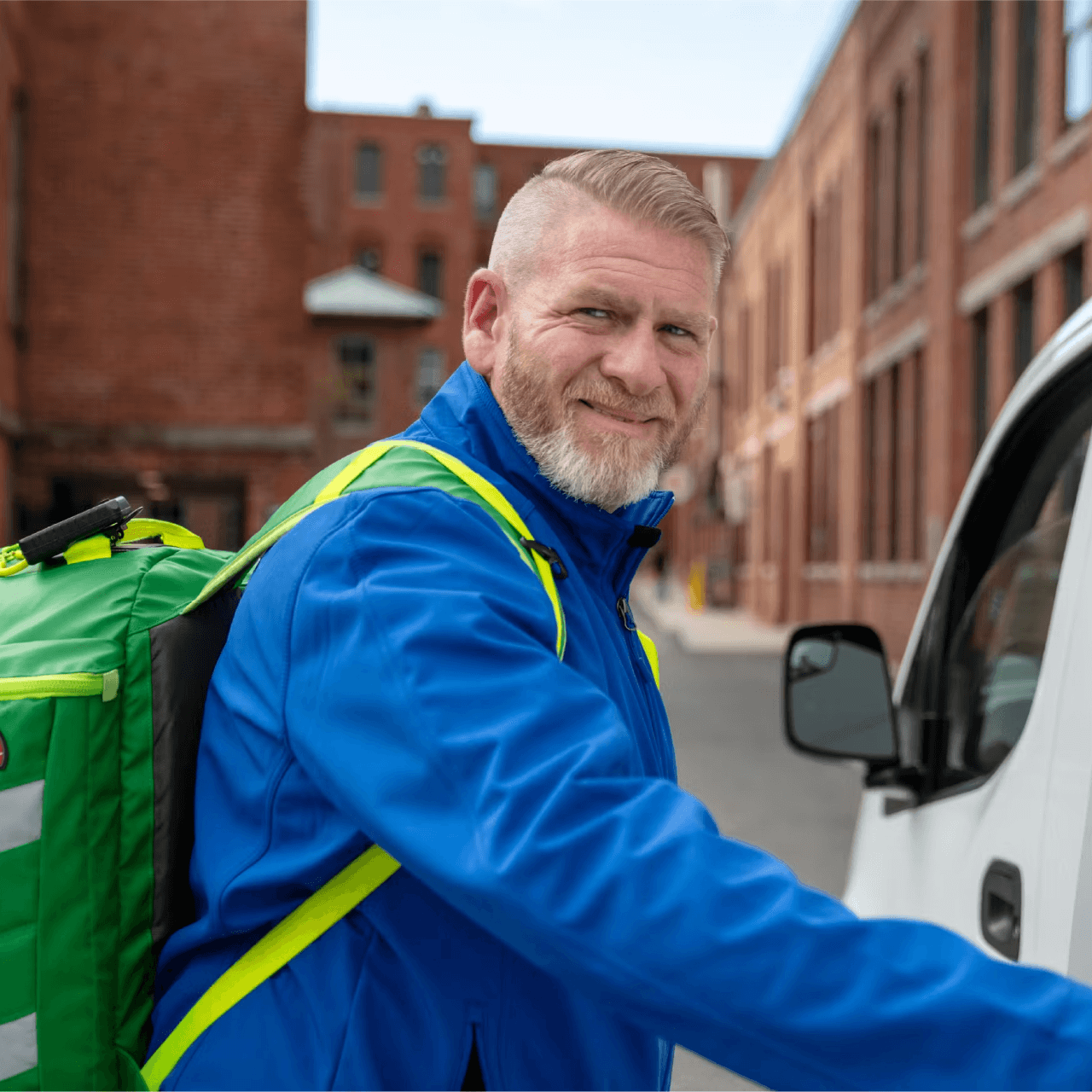 Cityblock urgent care clinician wears a blue jacket while smiling and opening a van door.