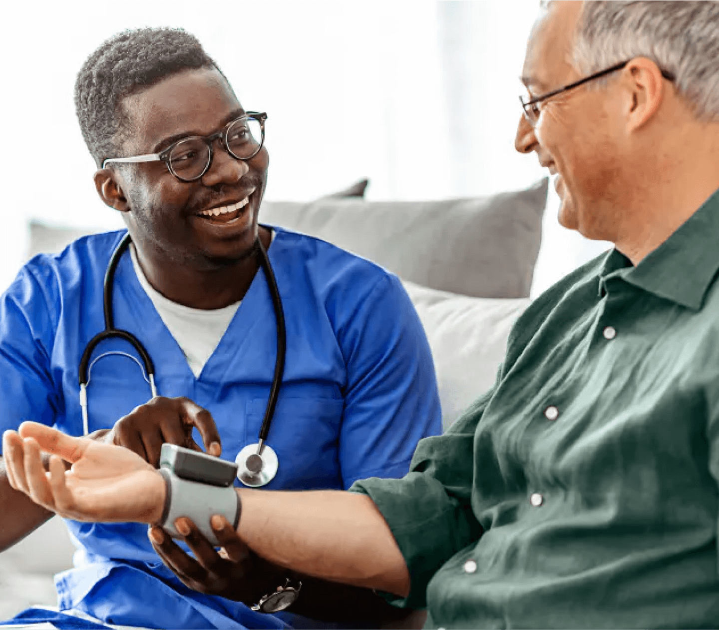 Medical professional checks the pulse of person while sitting on the couch at home