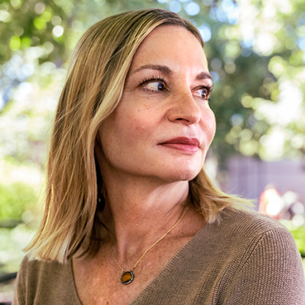 Portrait of a blonde woman looking to the right while wearing a brown sweater.