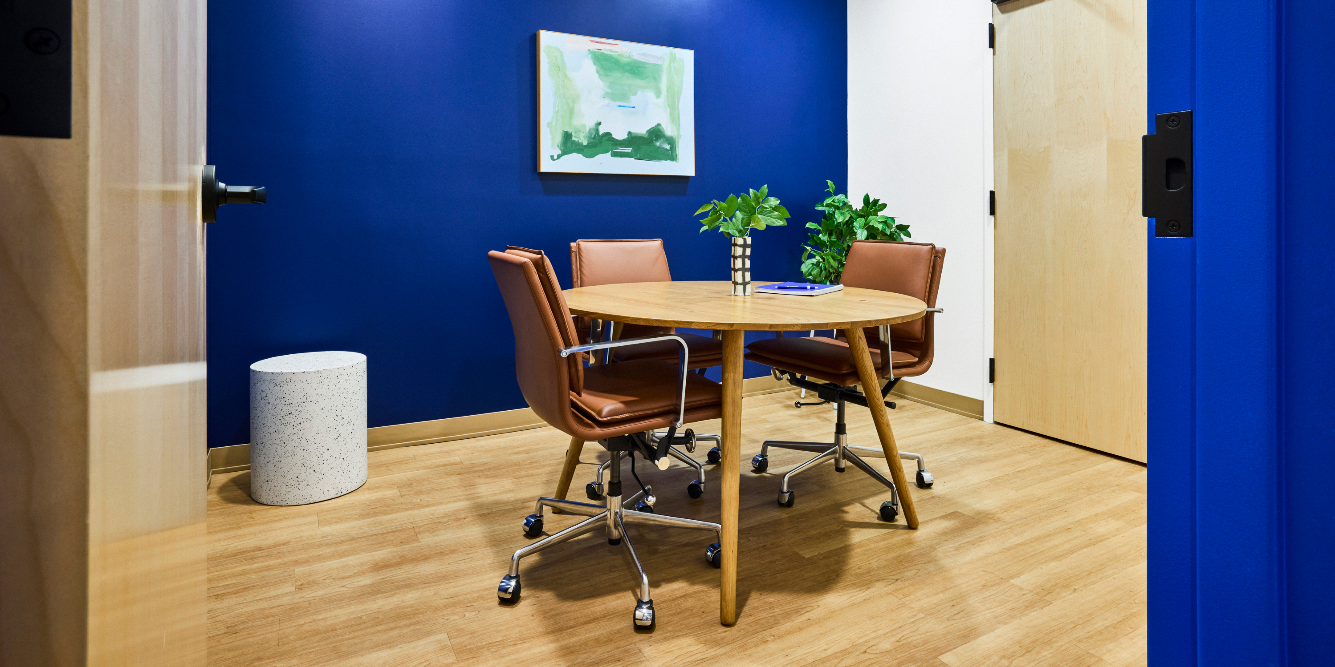 Meeting room with three tan chairs around a circular table.