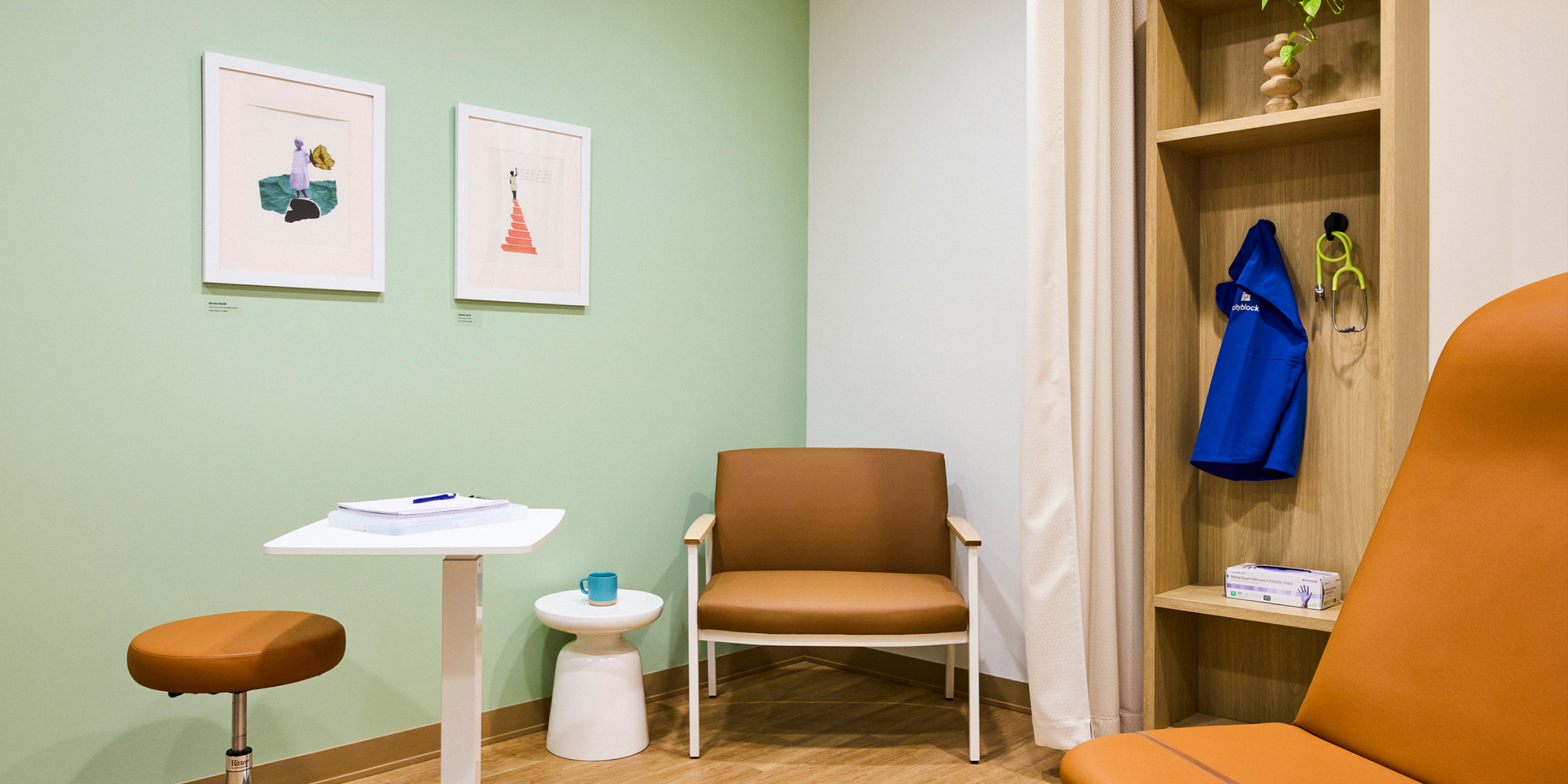 Exam room with tan furniture and standing shelf.