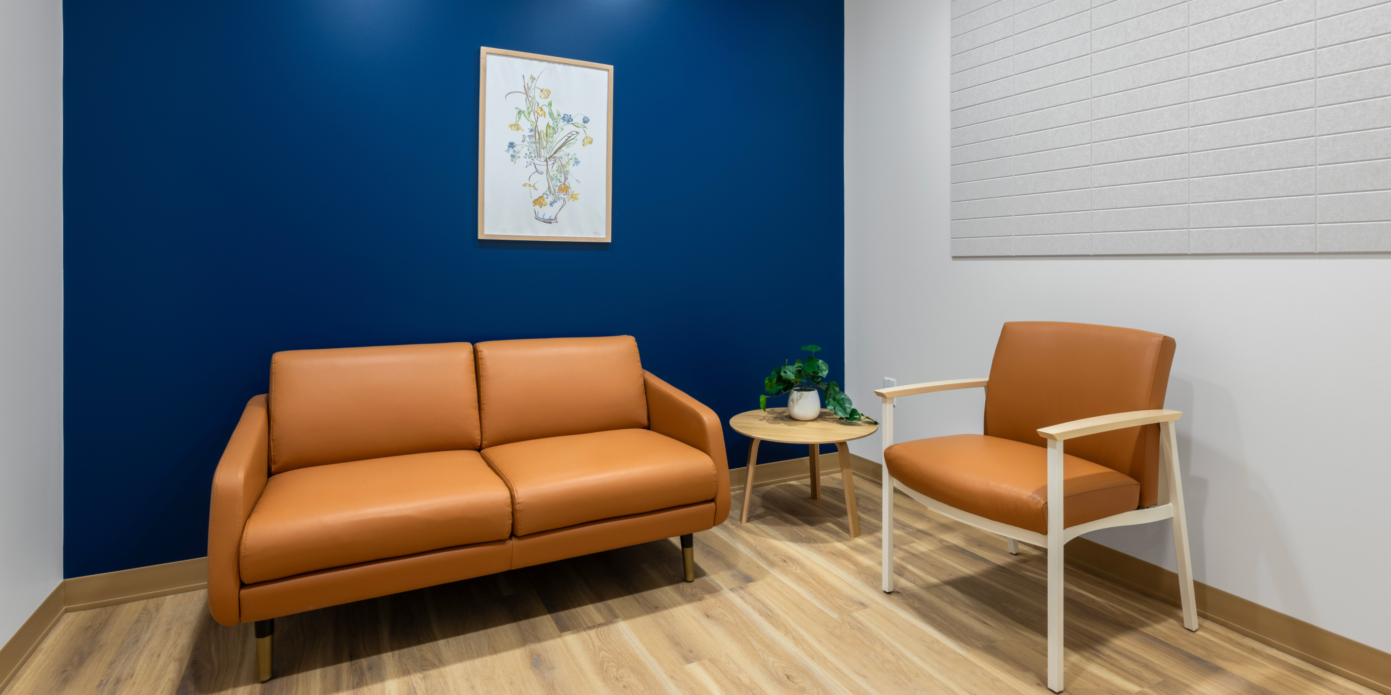Room with navy blue and white walls, featuring a tan couch and chair.