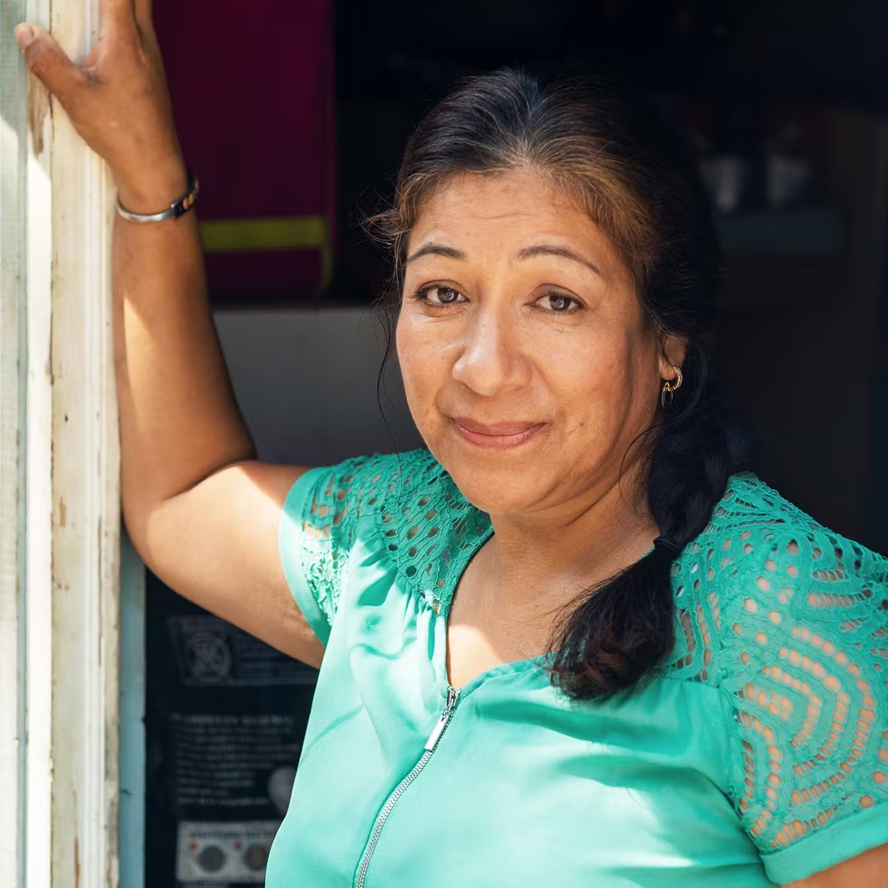 Woman wearing a blue teal blouse smiles optimistically.