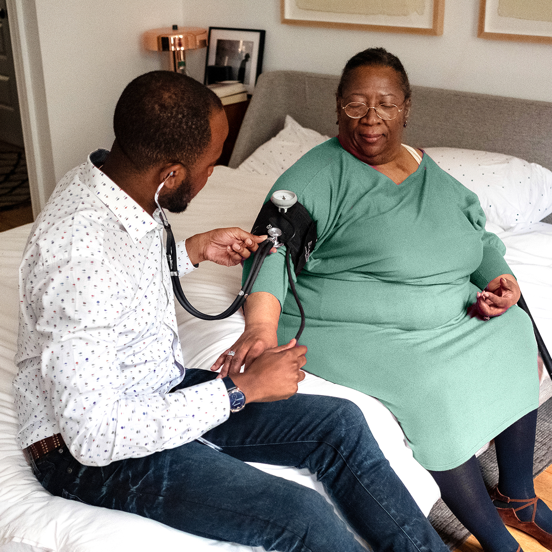 Photo of a medical provider taking the blood pressure of an elderly woman at home