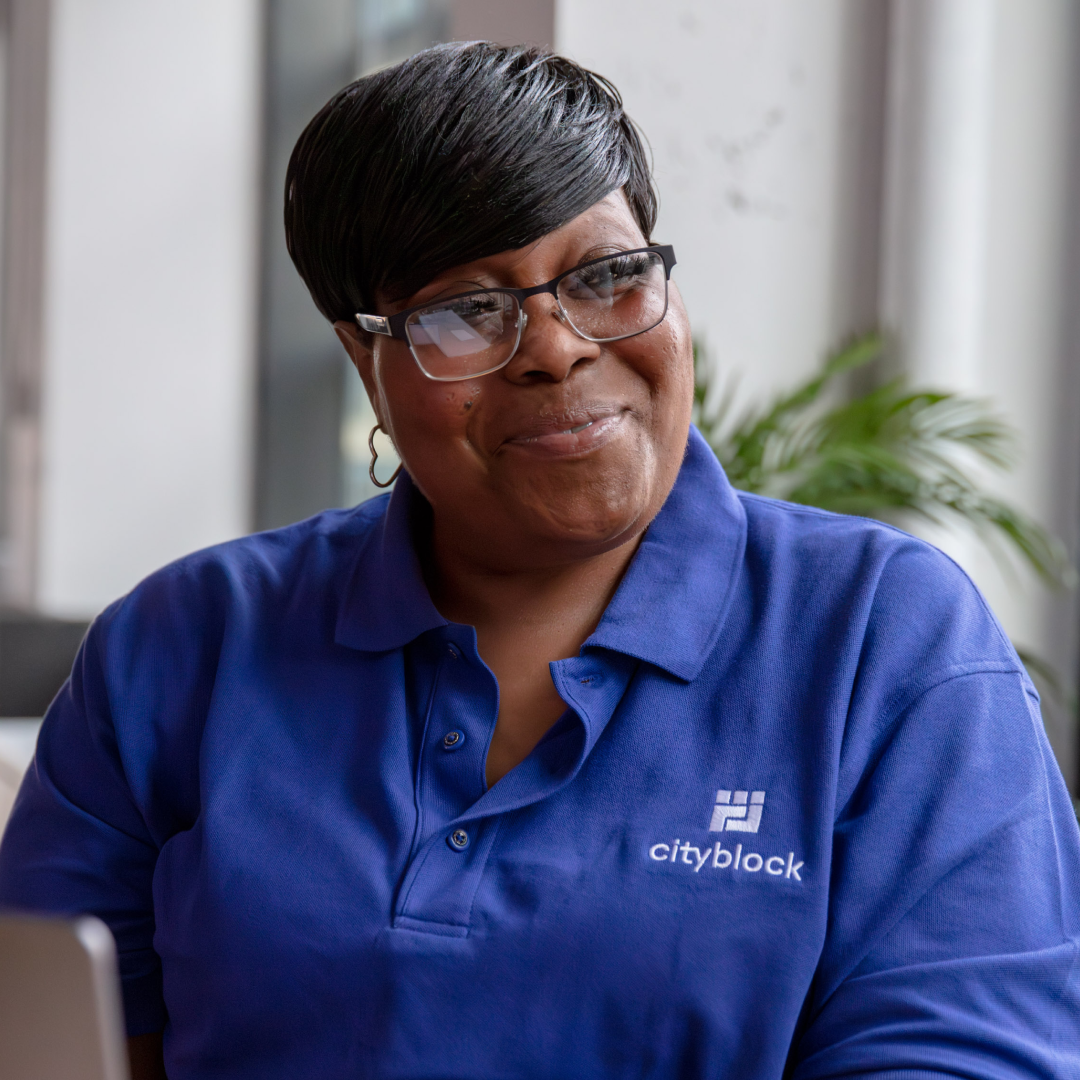Photo of a Cityblock employee wearing a blue polo while smiling proudly