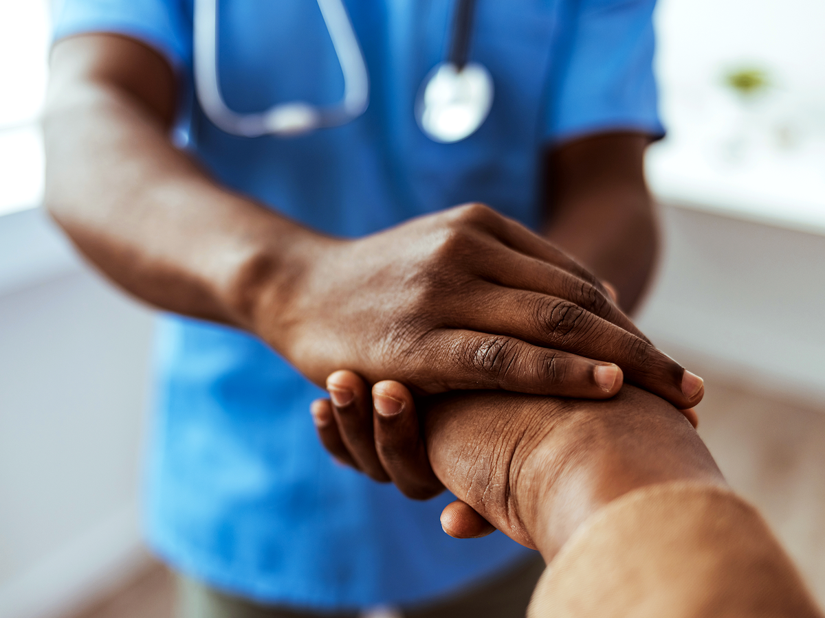 Photo of a nurse holding the hand of someone reaching out