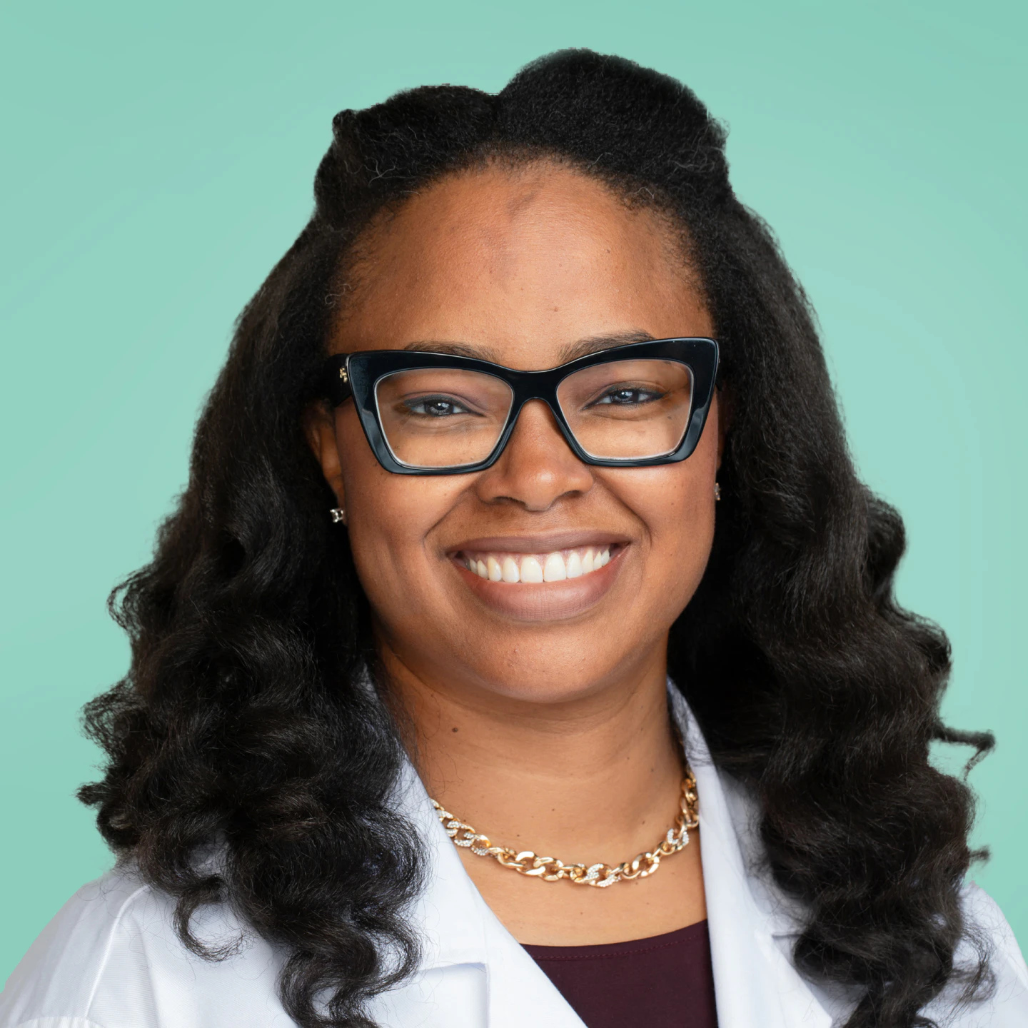 Photo of a Cityblock provider wearing a white lab coat over a teal background.