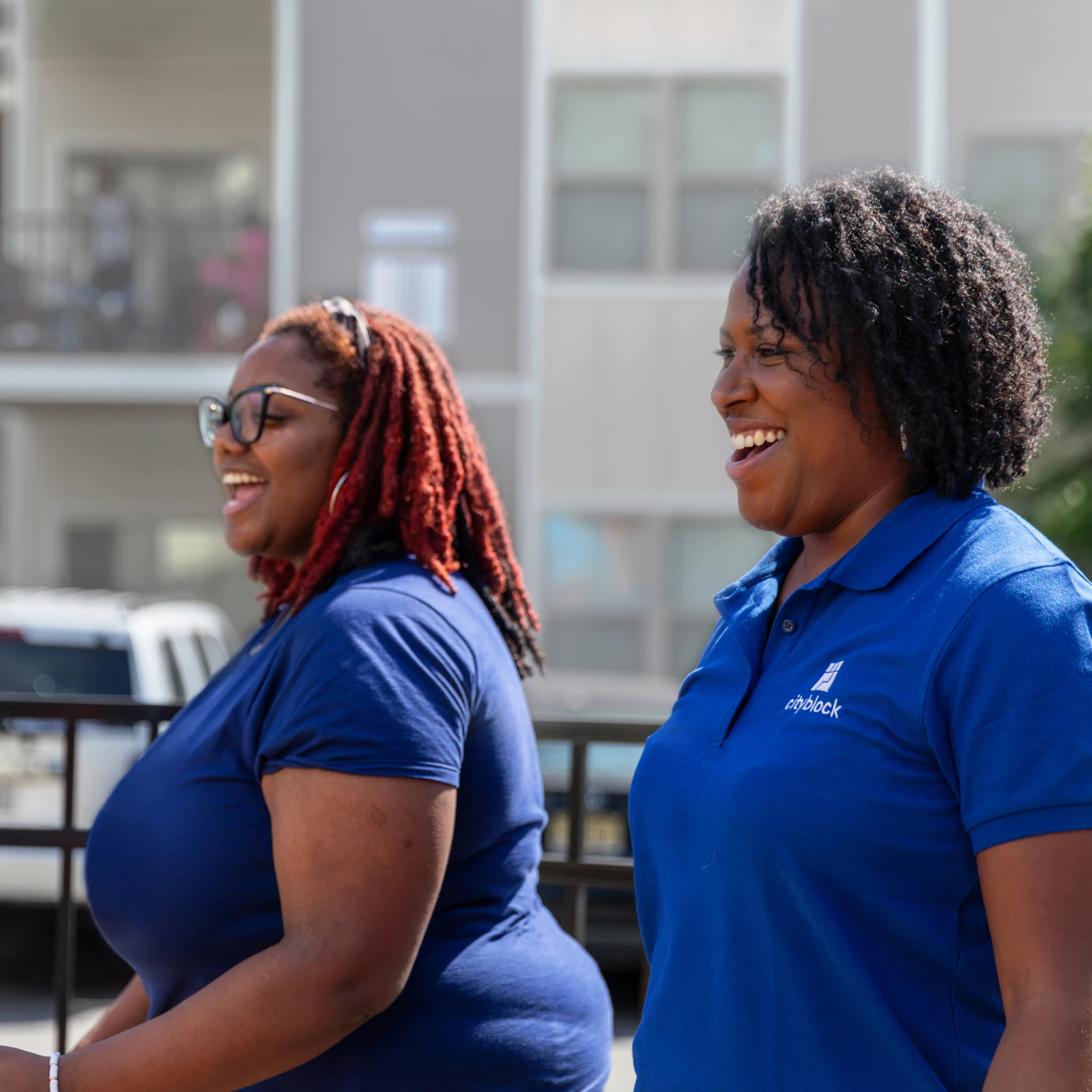 Image of a community health partner and member in blue shirts, walking outside in a neighborhood.