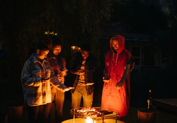 Vier Freunde Grillen an einer Feuerstelle auf dem Campingplatz Jungfrau Lauterbrunnen im Berner Oberland