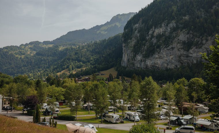 campsite with campervans in the summer and mountains behind it