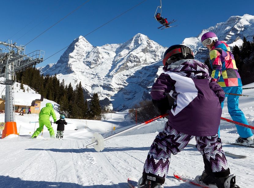Kinderskigebiet mit schneebedeckten Bergen im Hintergrund, Familie mit Kindern im Vordergrund