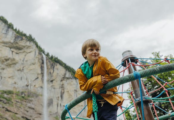 Kind auf der Kletterpyramide auf dem Campingplatz Jungfrau Lauterbrunnen mit dem Staubbachfall im Hintergrund