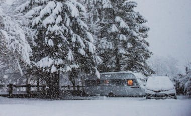 Camper in Winterlandschaft Schneefall verschneite Bäume